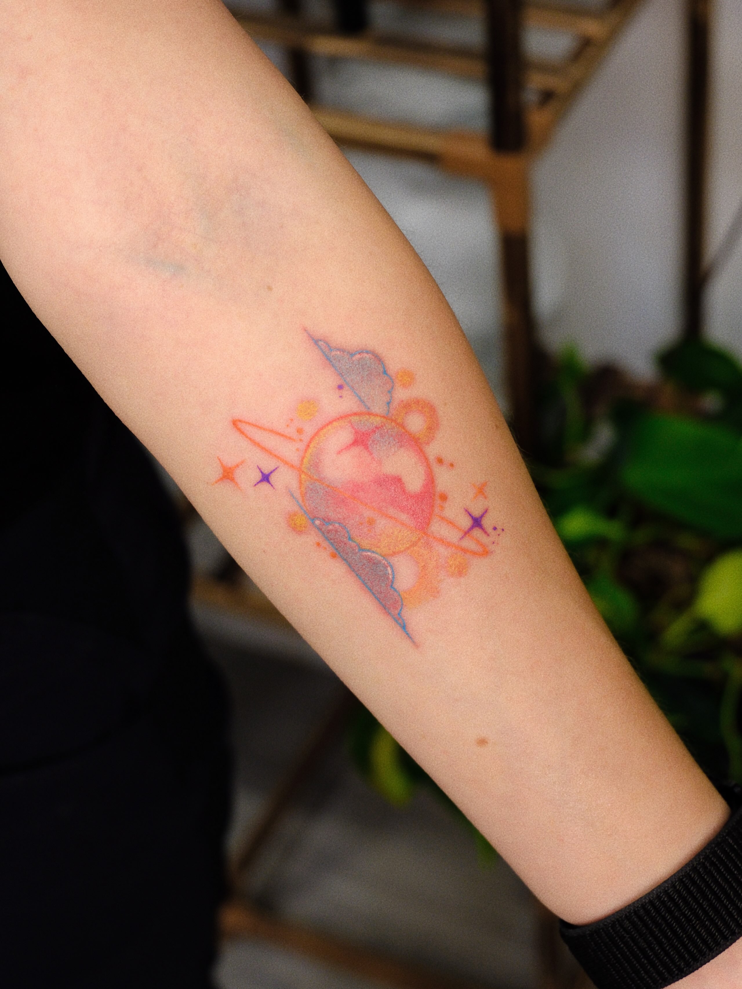 Space-themed watercolor tattoo on the forearm by rita_tattooist