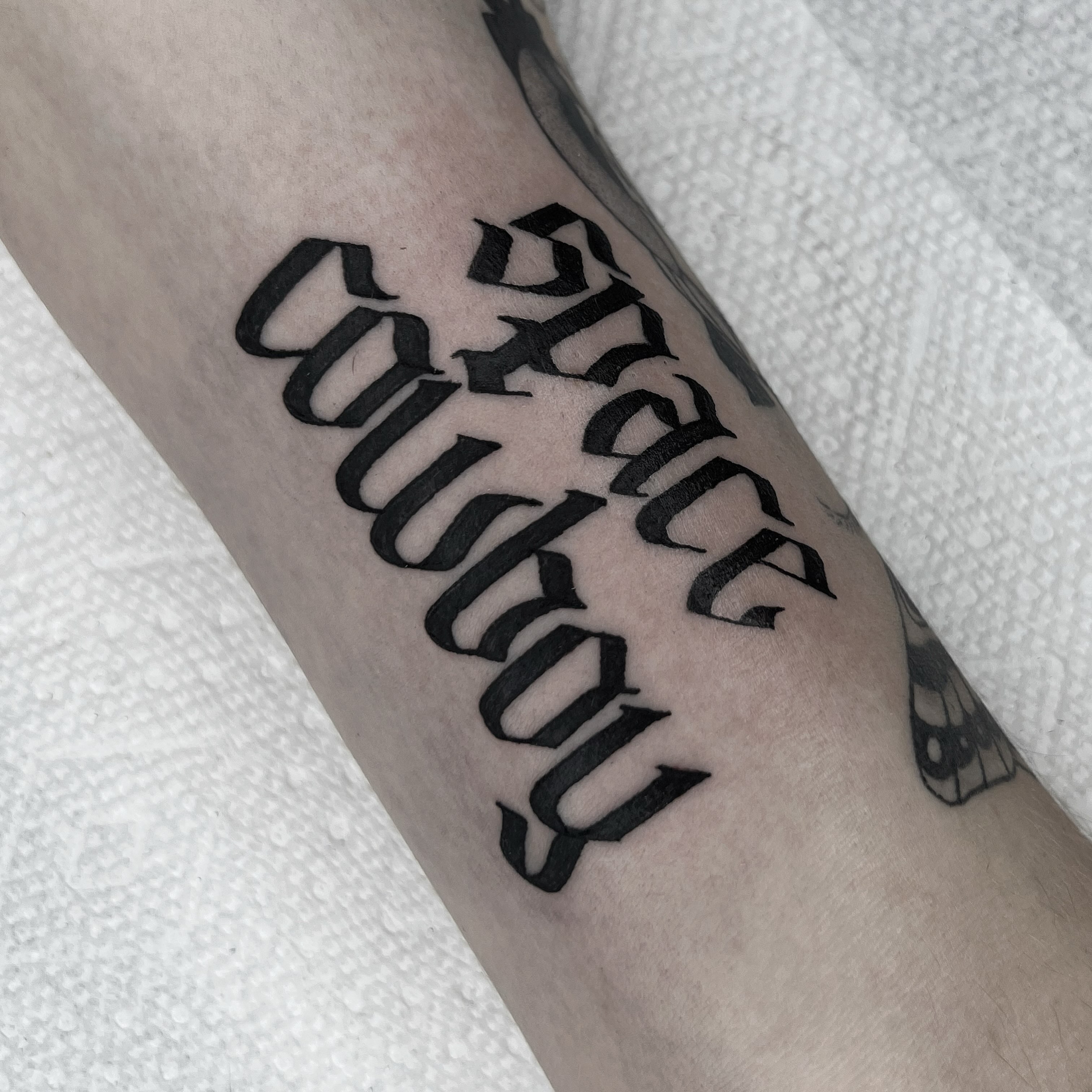 Space cowboy lettering script tattoo on the forearm by 𝑴𝑬𝑮𝑨𝑵 𝑪𝑳𝑰𝑭𝑻𝑶𝑵, Cincinnati, Ohio