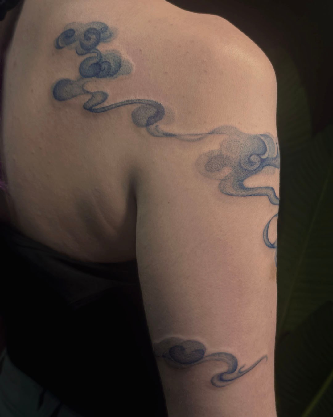 Smoke black and grey tattoo on the upper arm by Erin Isaacs