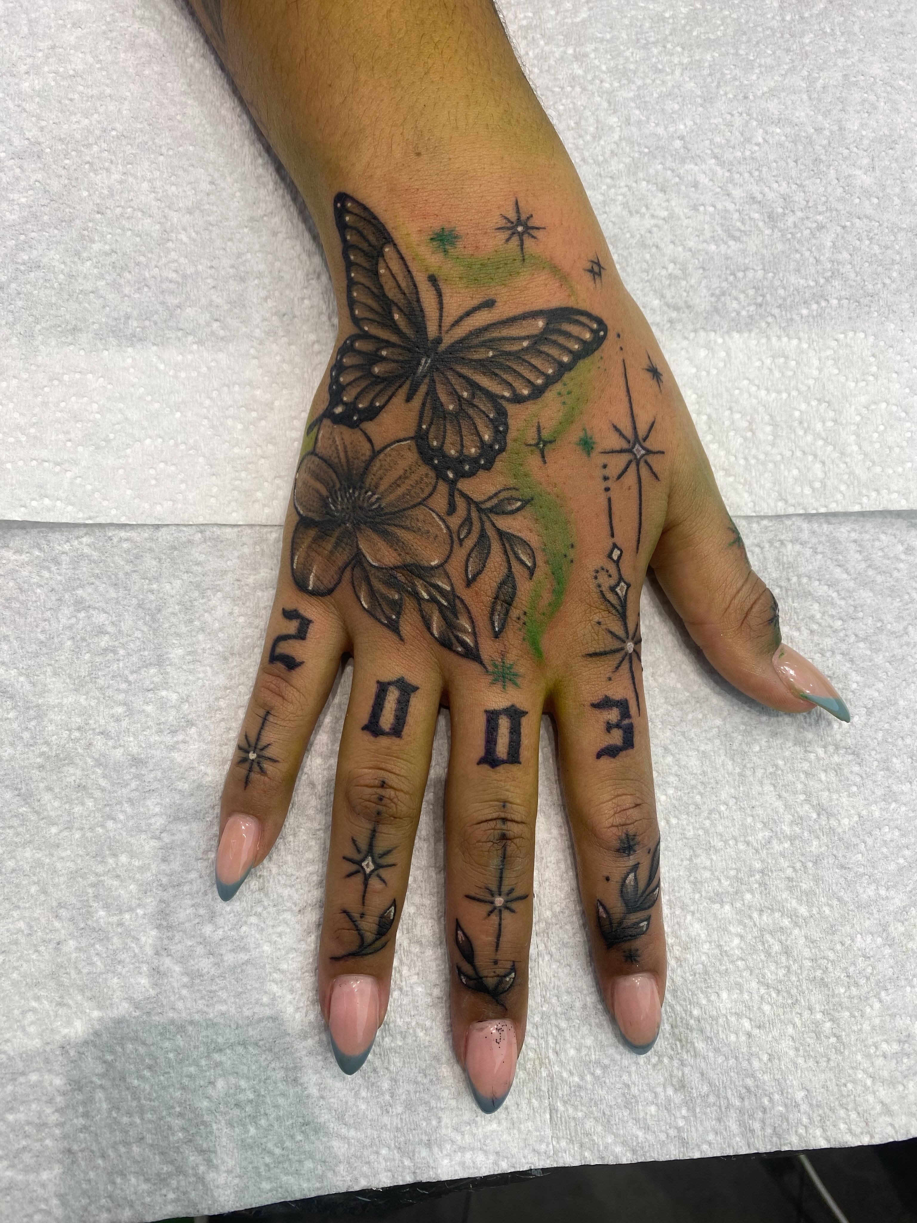 Butterfly and floral black and grey tattoo on the hand by @dom_macio_tattoo