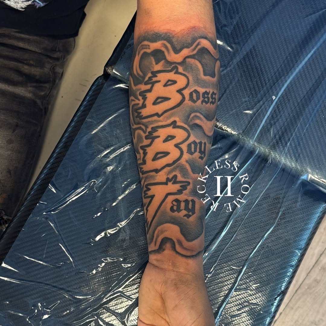 Boss boy black and grey tattoo on the forearm by Rome