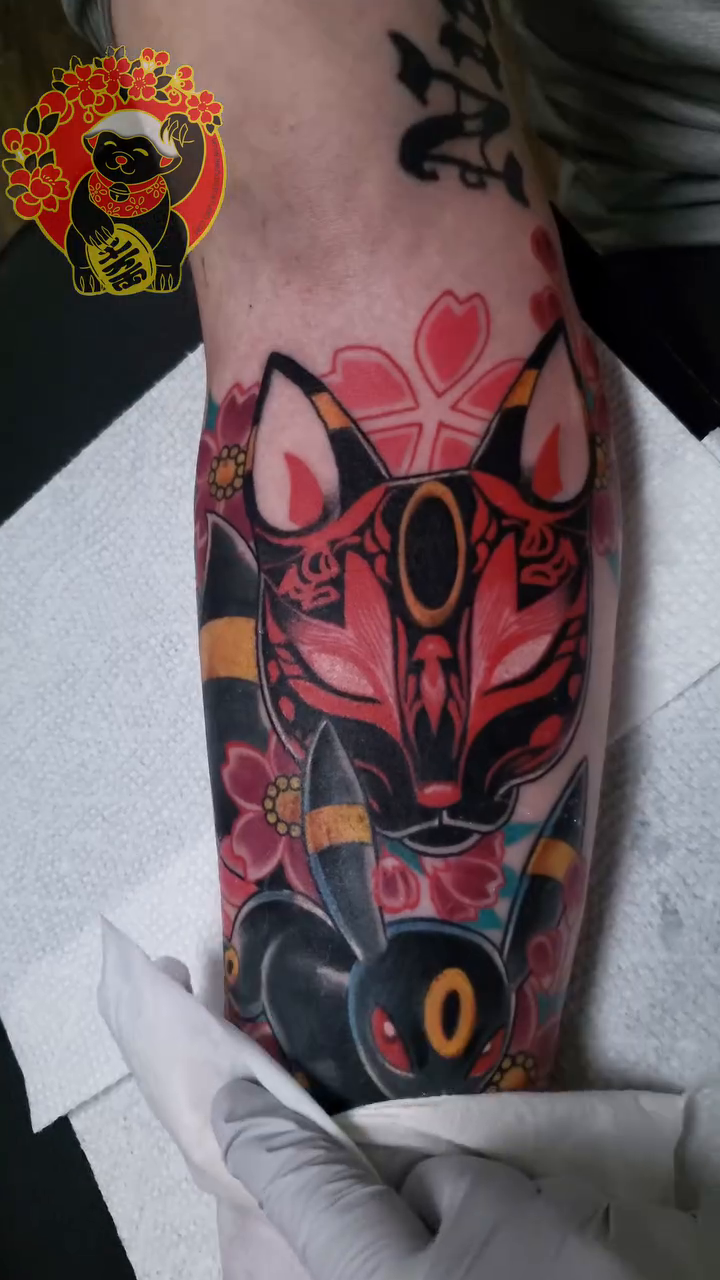 Kitsune mask and Umbreon new school tattoo on the forearm by Lillian Honeybadger