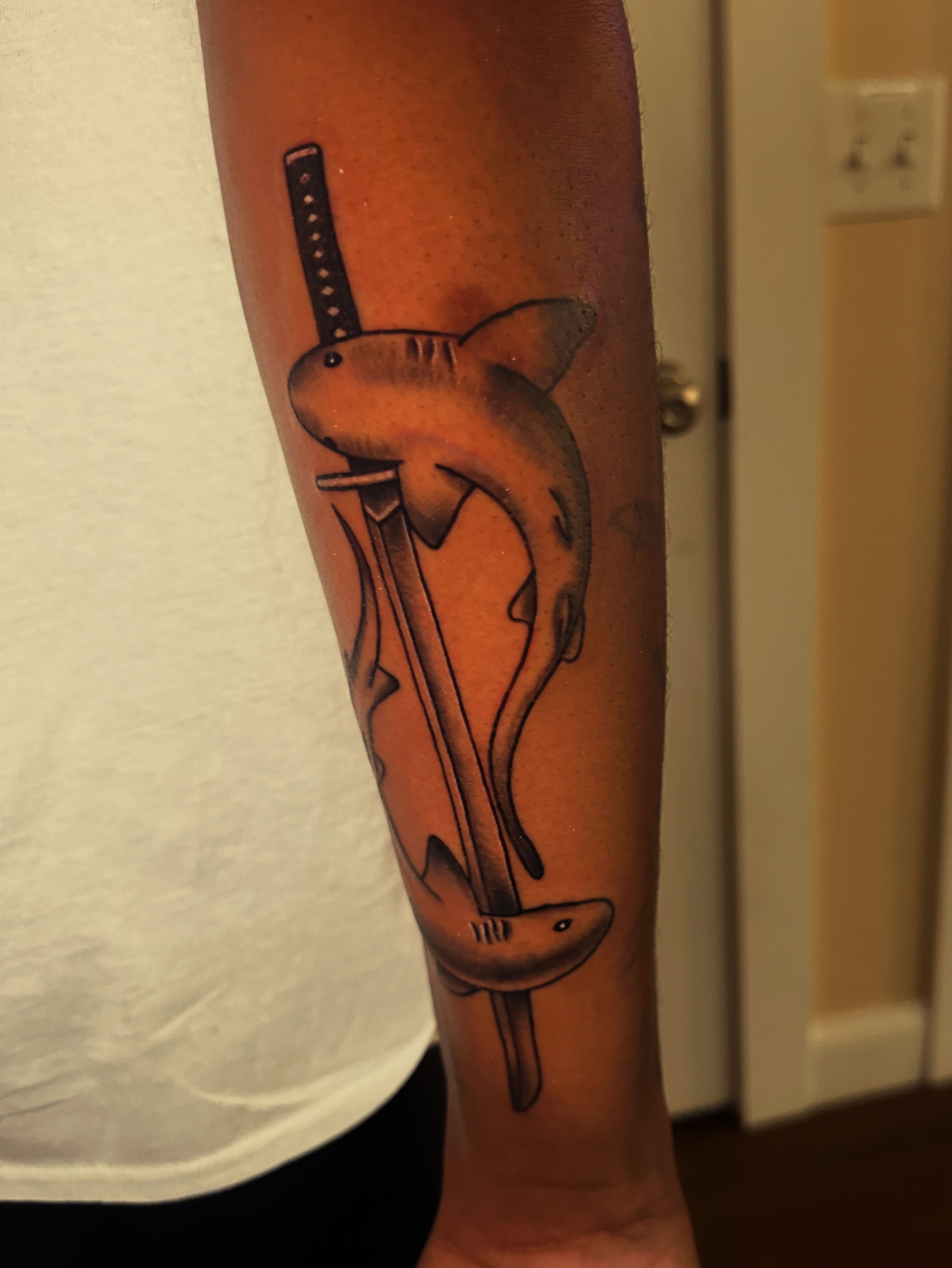 Shark and sword black and grey tattoo on the forearm by Drew’s Tattoos (NH)