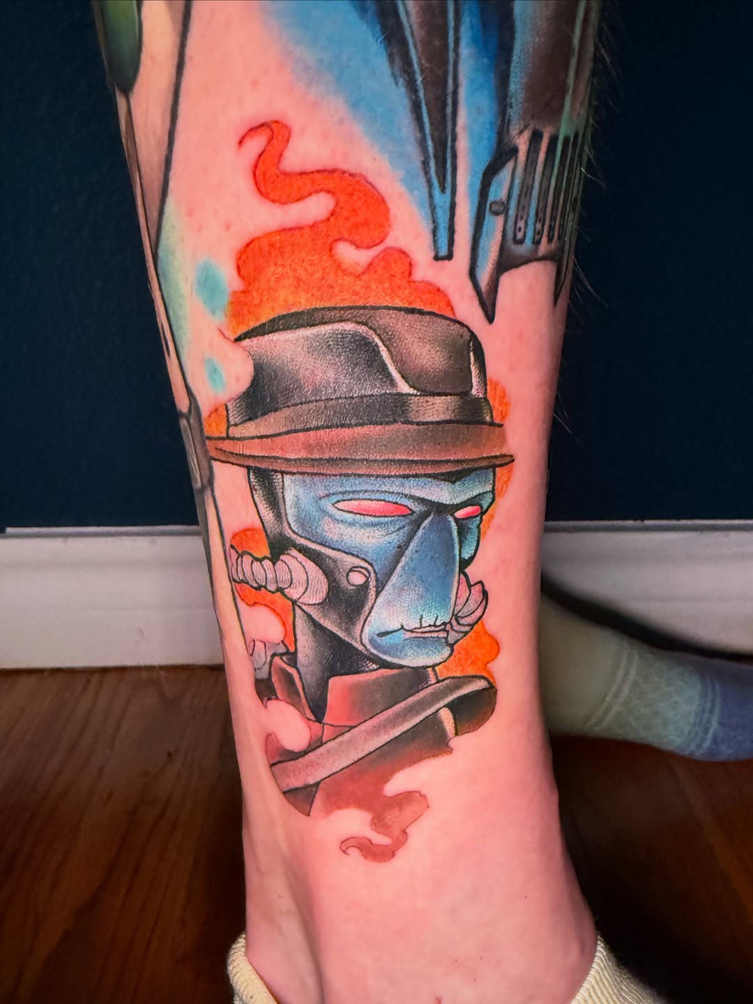 Character with hat and mask tattoo on the forearm by Erin Peterson