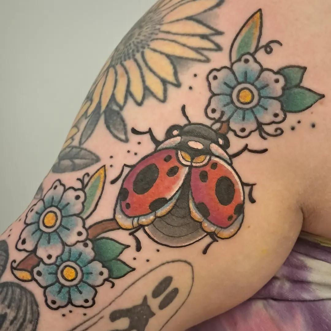 Ladybug and flowers American traditional tattoo on the shoulder by Erika Hollingsworth