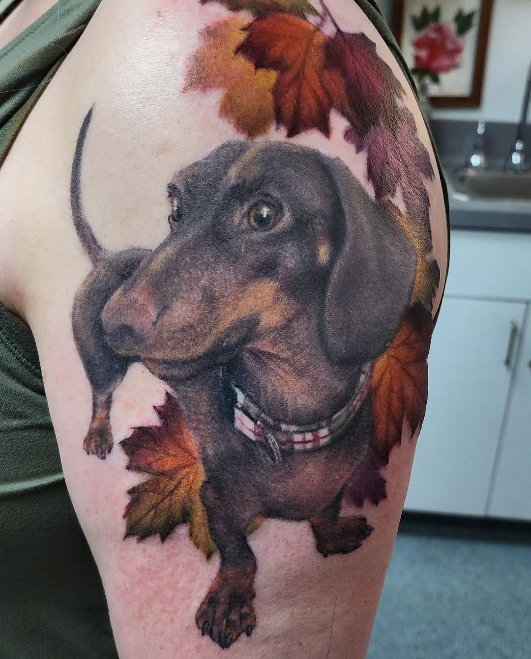 Dachshund realism tattoo on the upper arm by Katie Palmer