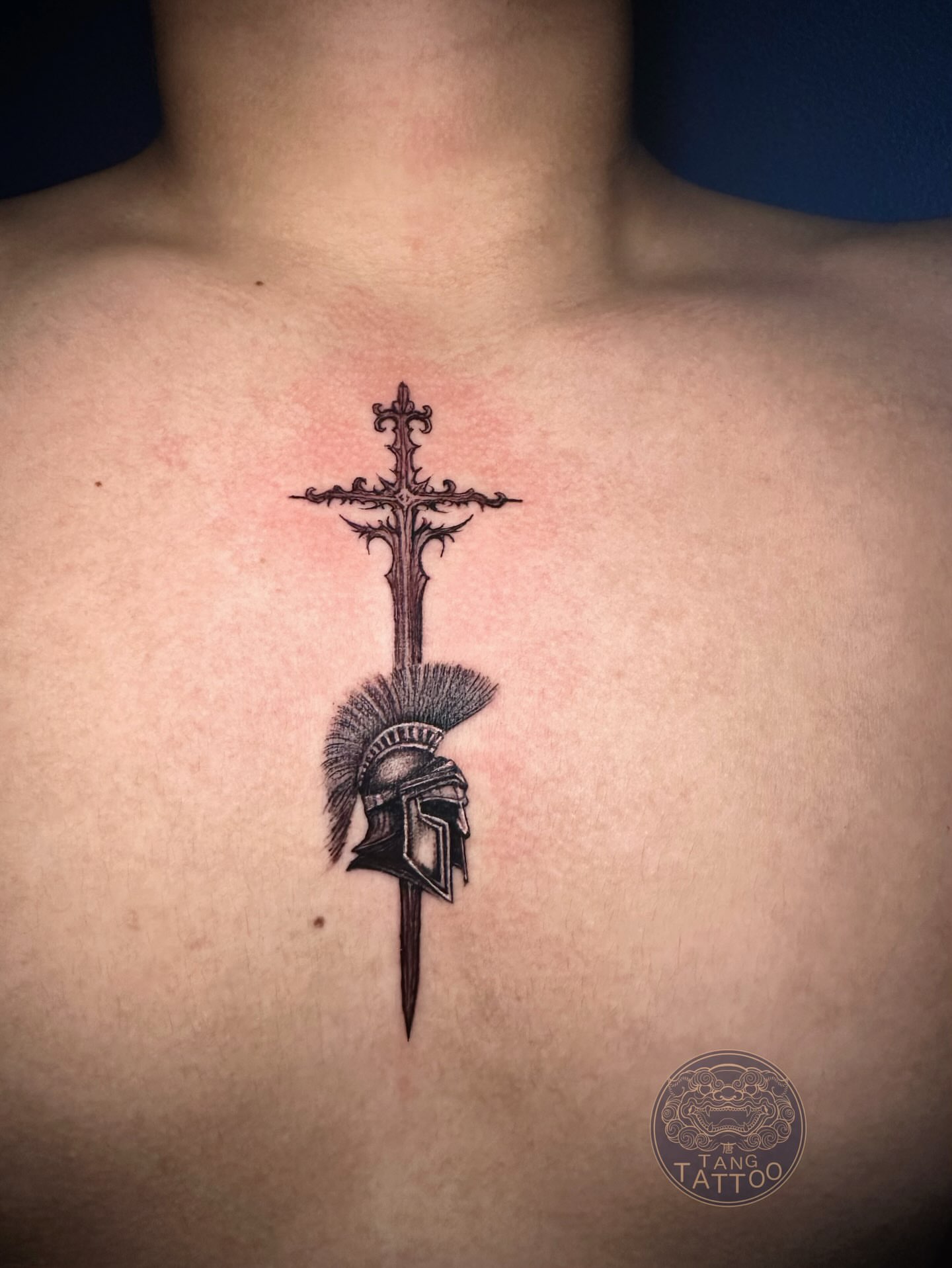 Cross with helmet black and grey tattoo on the chest by Tang tattoo, Houston, Texas