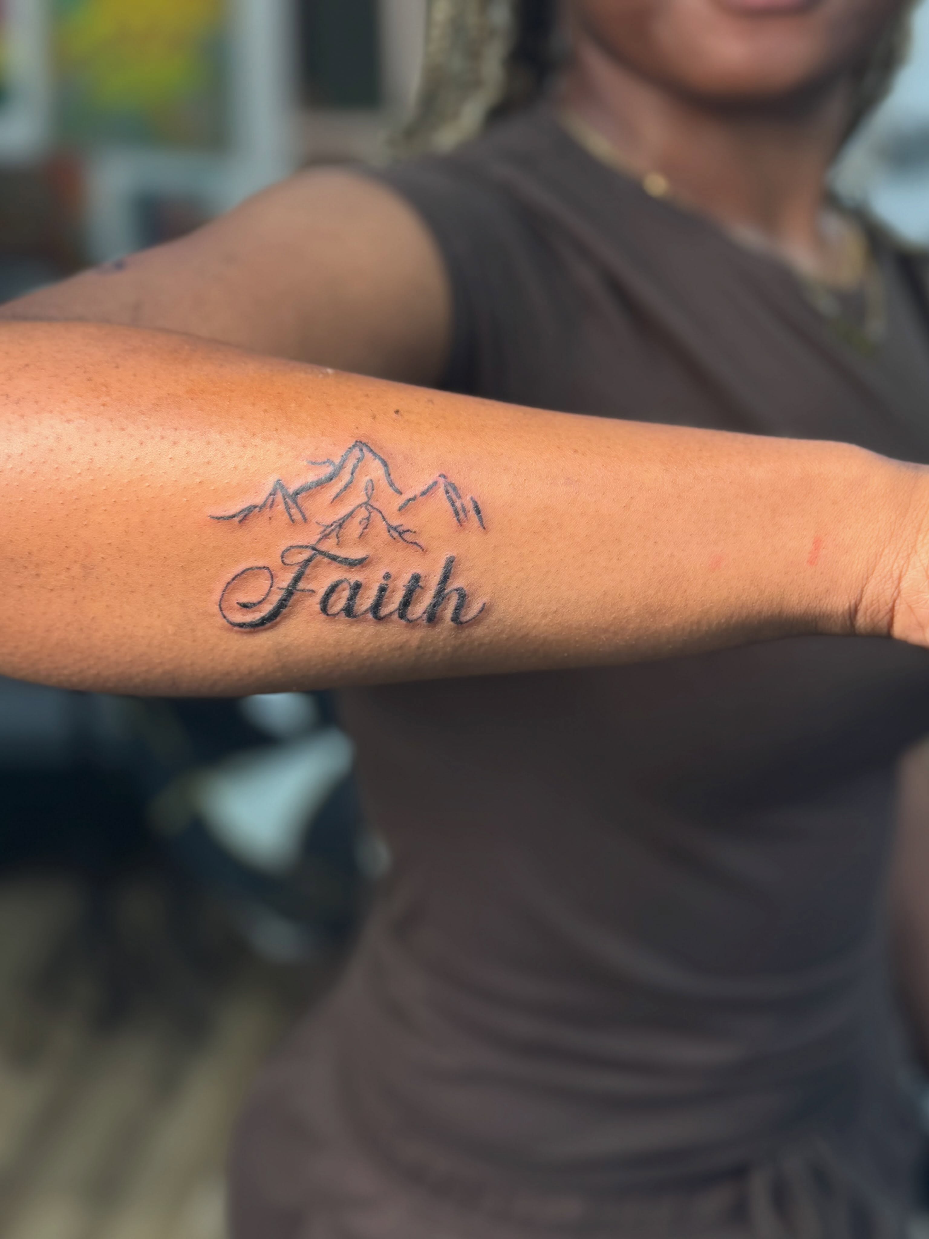 Mountain range with 'Faith' lettering script tattoo on the forearm by Charlotte Tattoo Artist💉