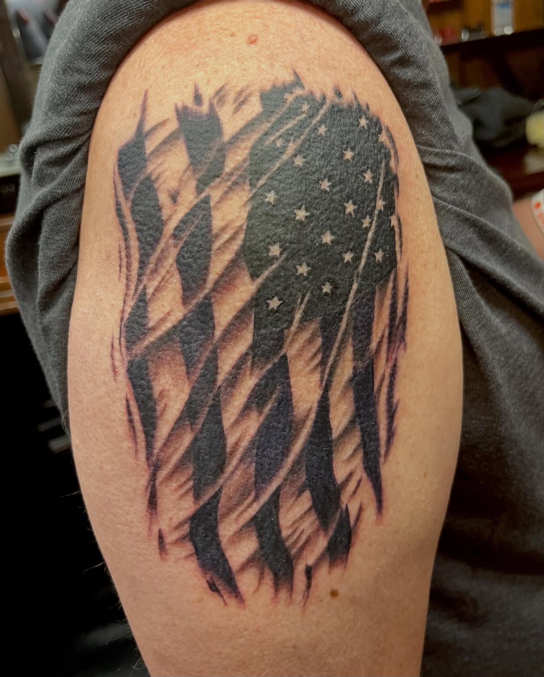 American flag black and grey tattoo on the shoulder by Kenny Buck