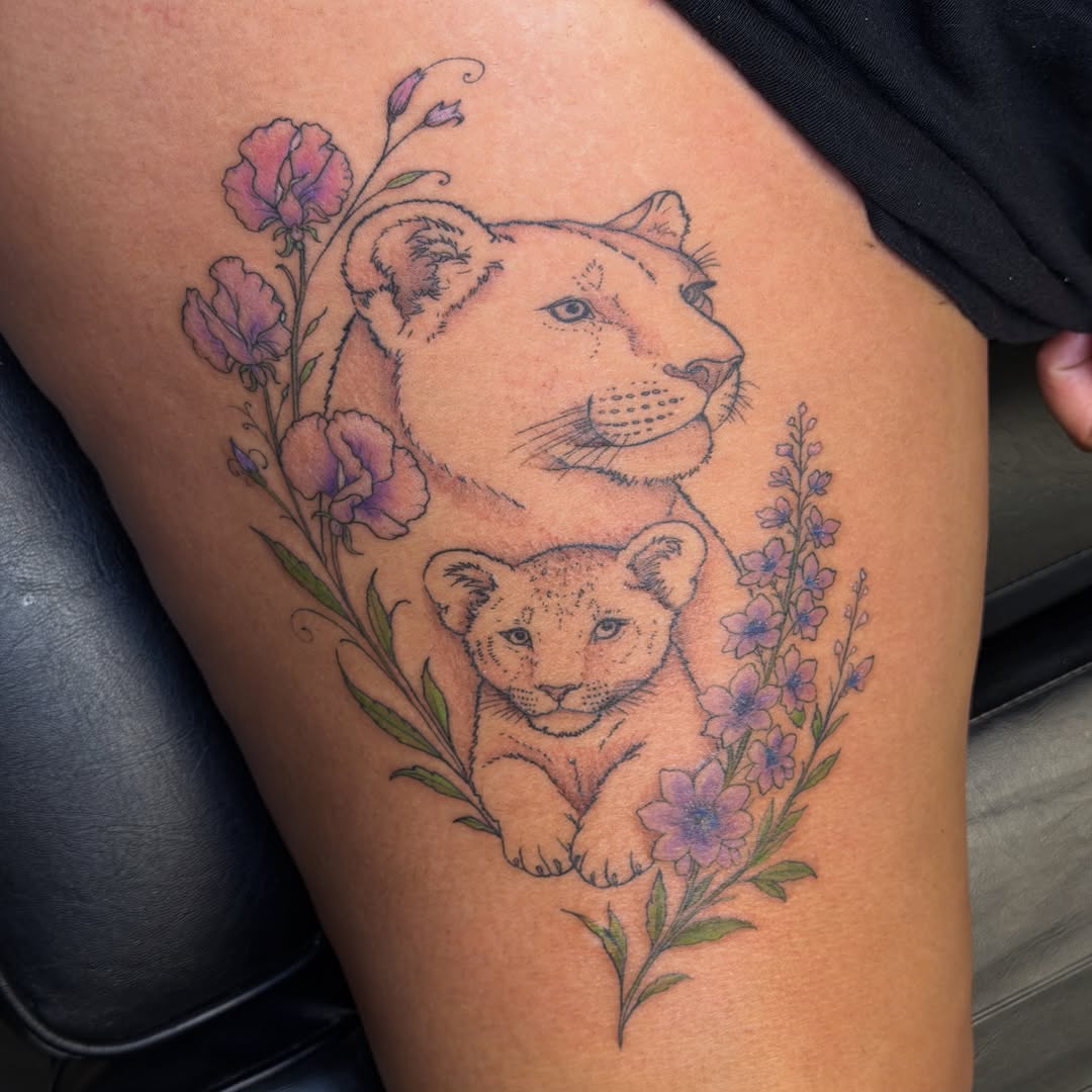 Lioness and cub with flowers fine line tattoo on the thigh by Pretty Ugly Tattoos