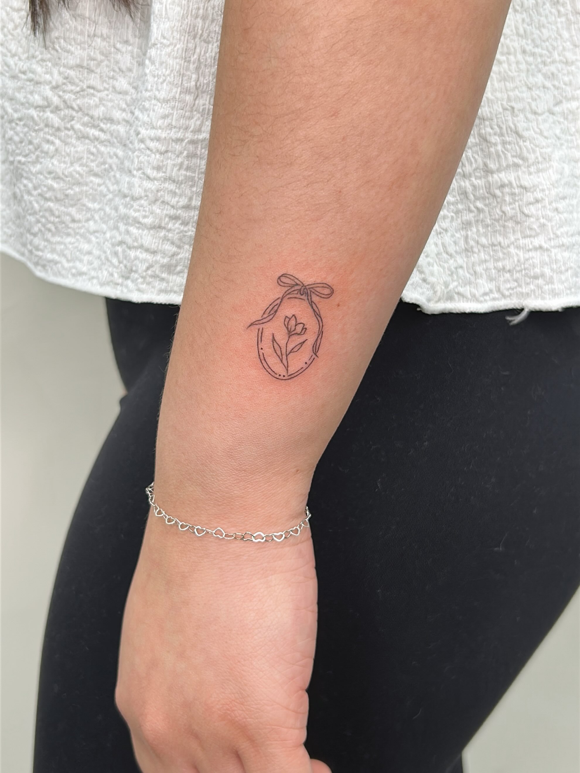 Flower in a pod fine line tattoo on the forearm by Harmony