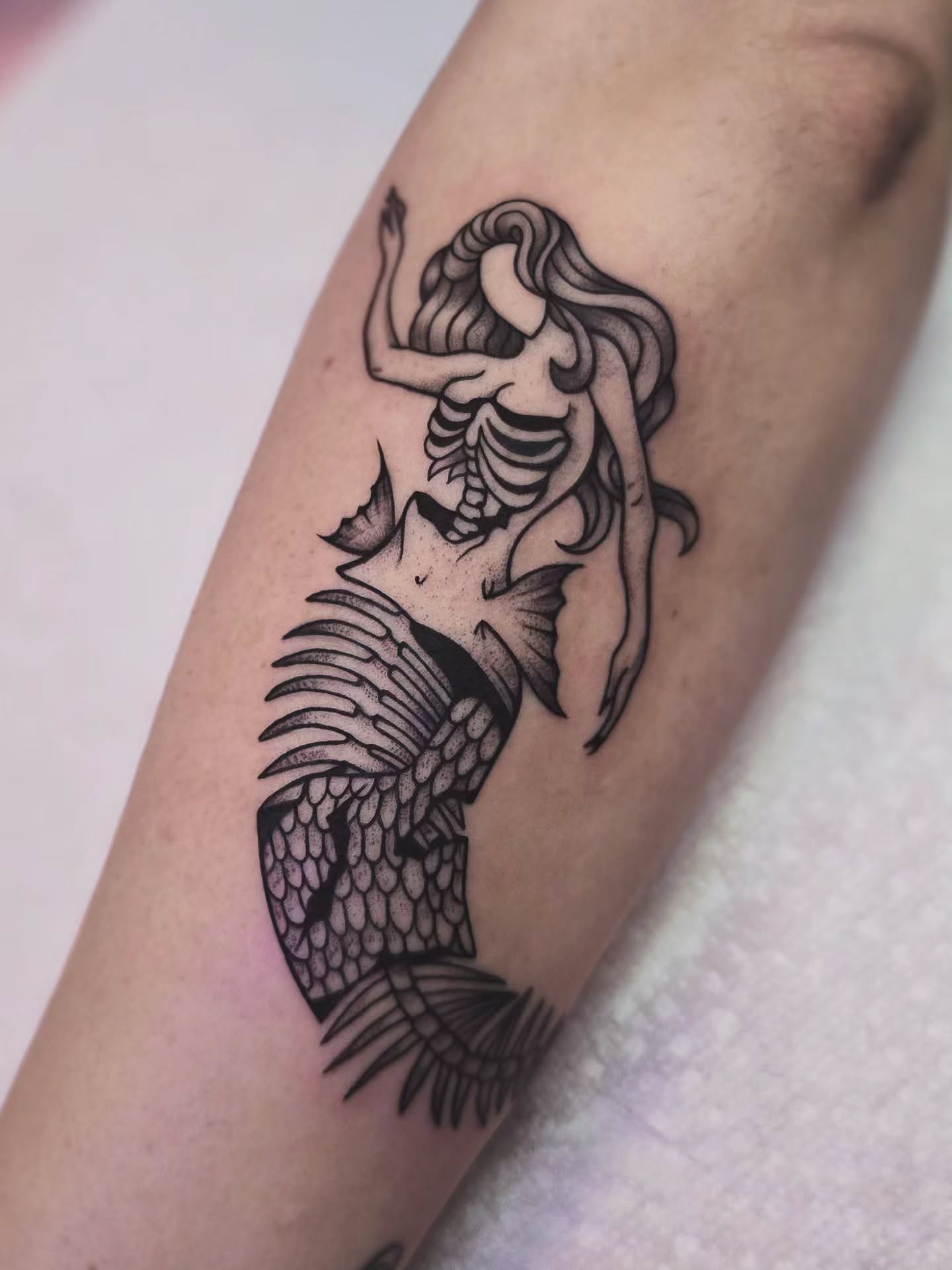 Mermaid skeleton black and grey tattoo on the forearm by Kirstie Lew Tattoo