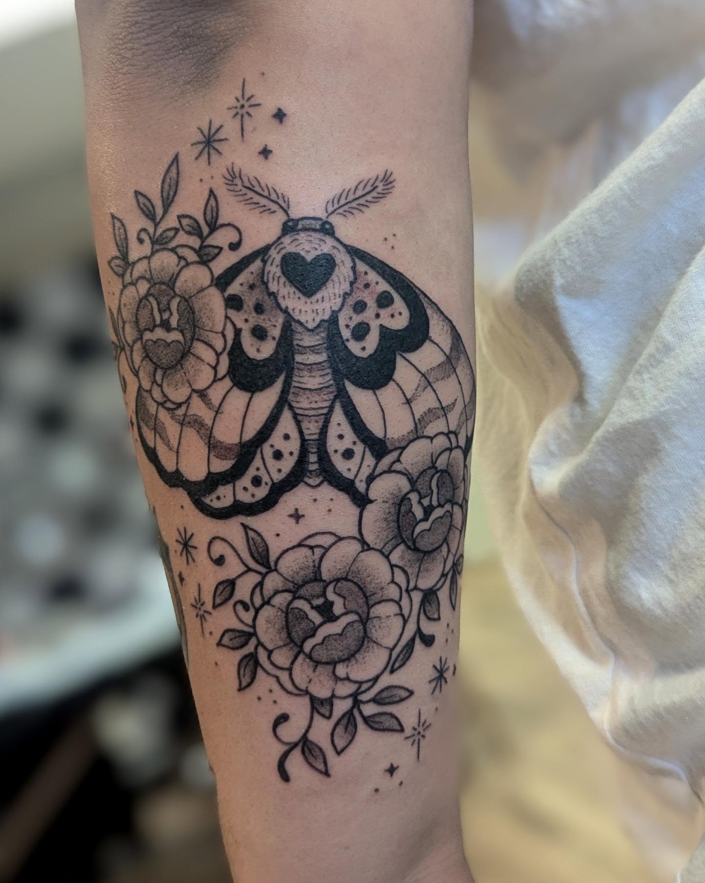 Moth and roses dotwork tattoo on the forearm by Dani Harkey