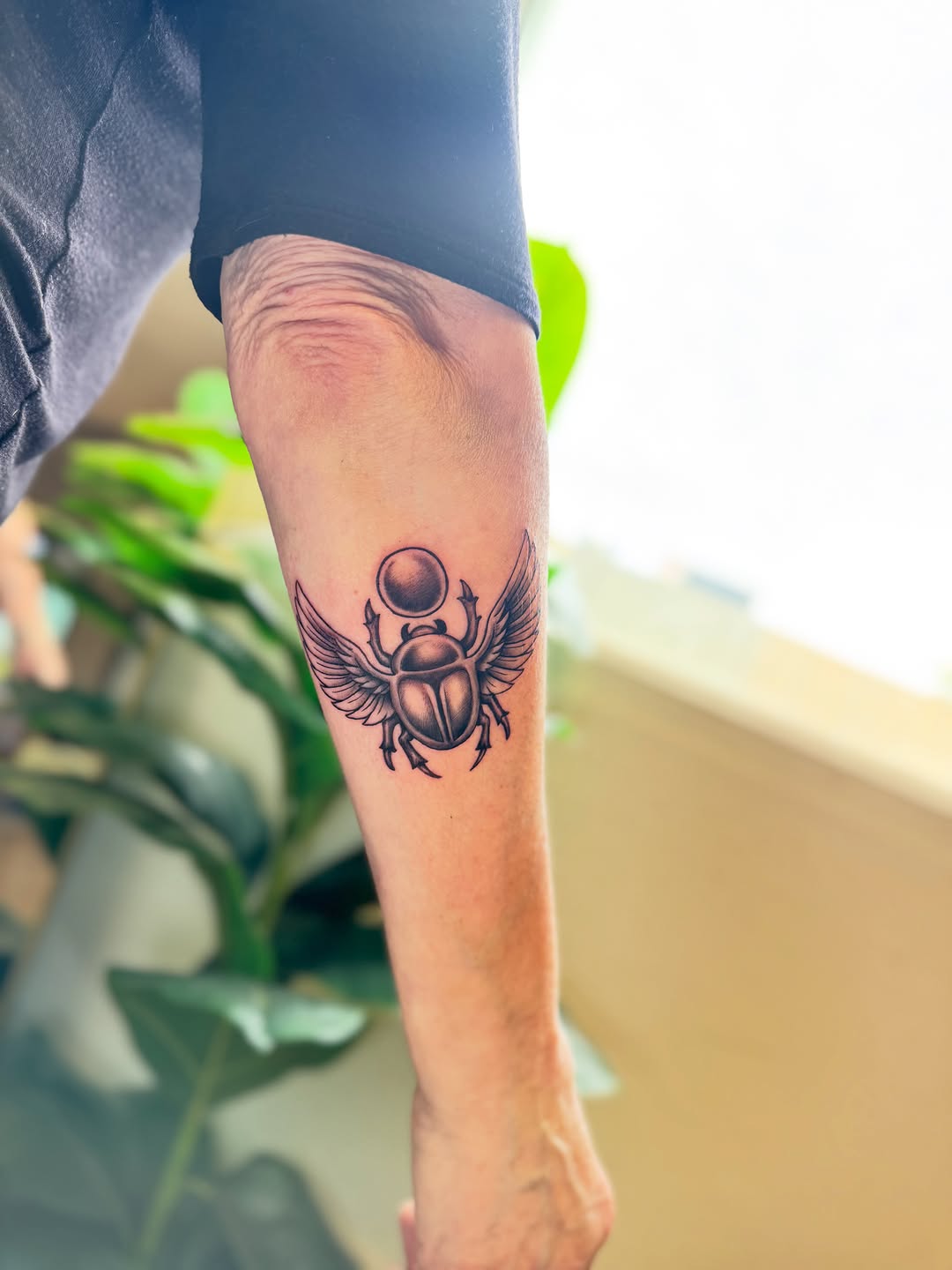 Winged scarab beetle fine line tattoo on the forearm by Monica Gonzalez