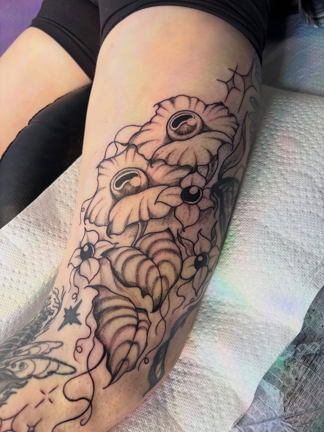 Surreal flowers with eyes dotwork tattoo on the thigh by Nashville Tattoo Artist