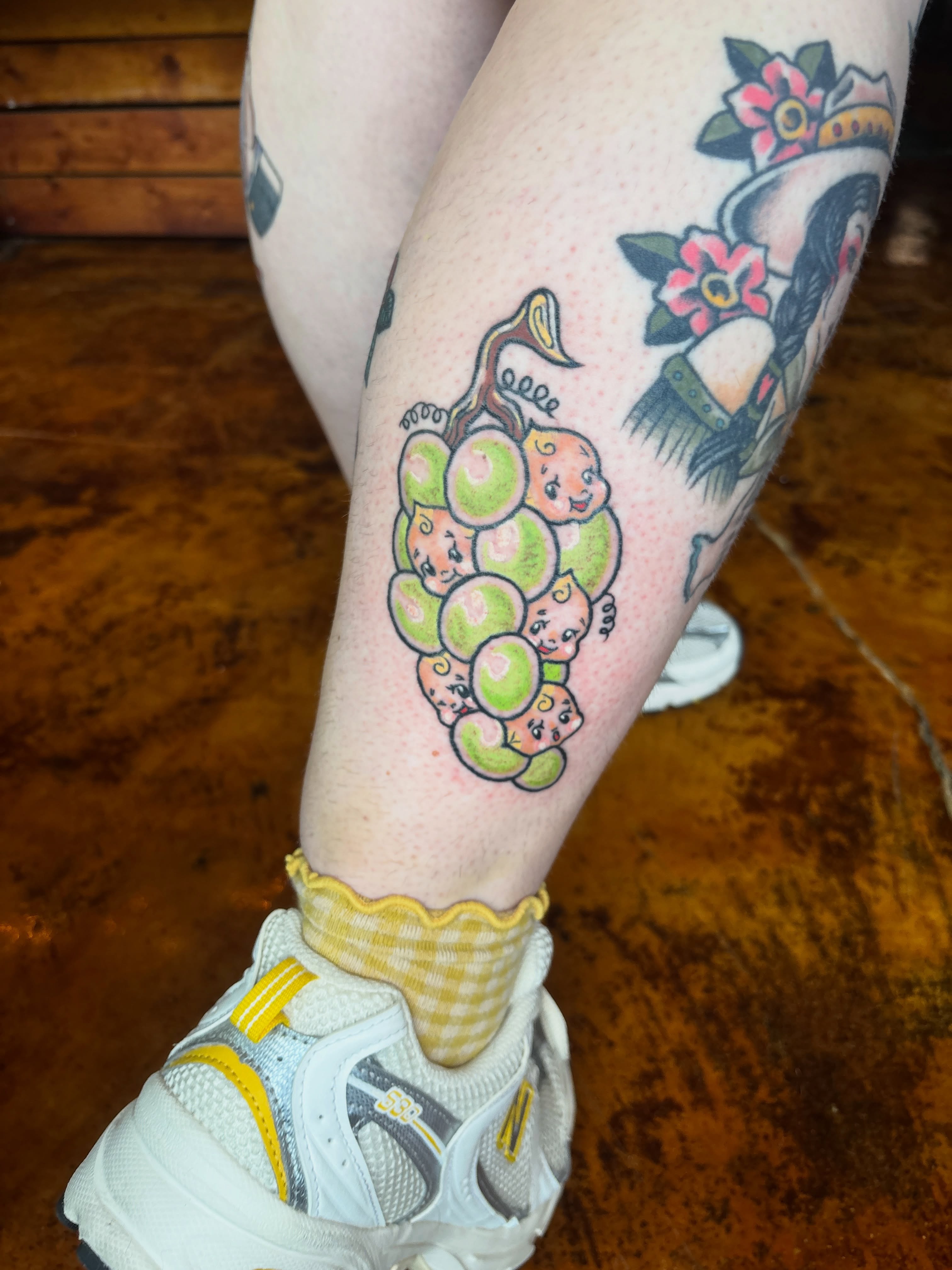 Grape cluster American traditional tattoo on the leg by Lilly Evans
