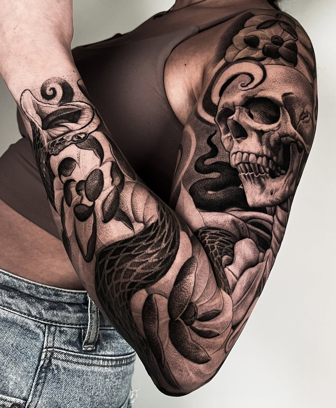 Skull and snake realism tattoo on the upper arm by Enrique Martinez
