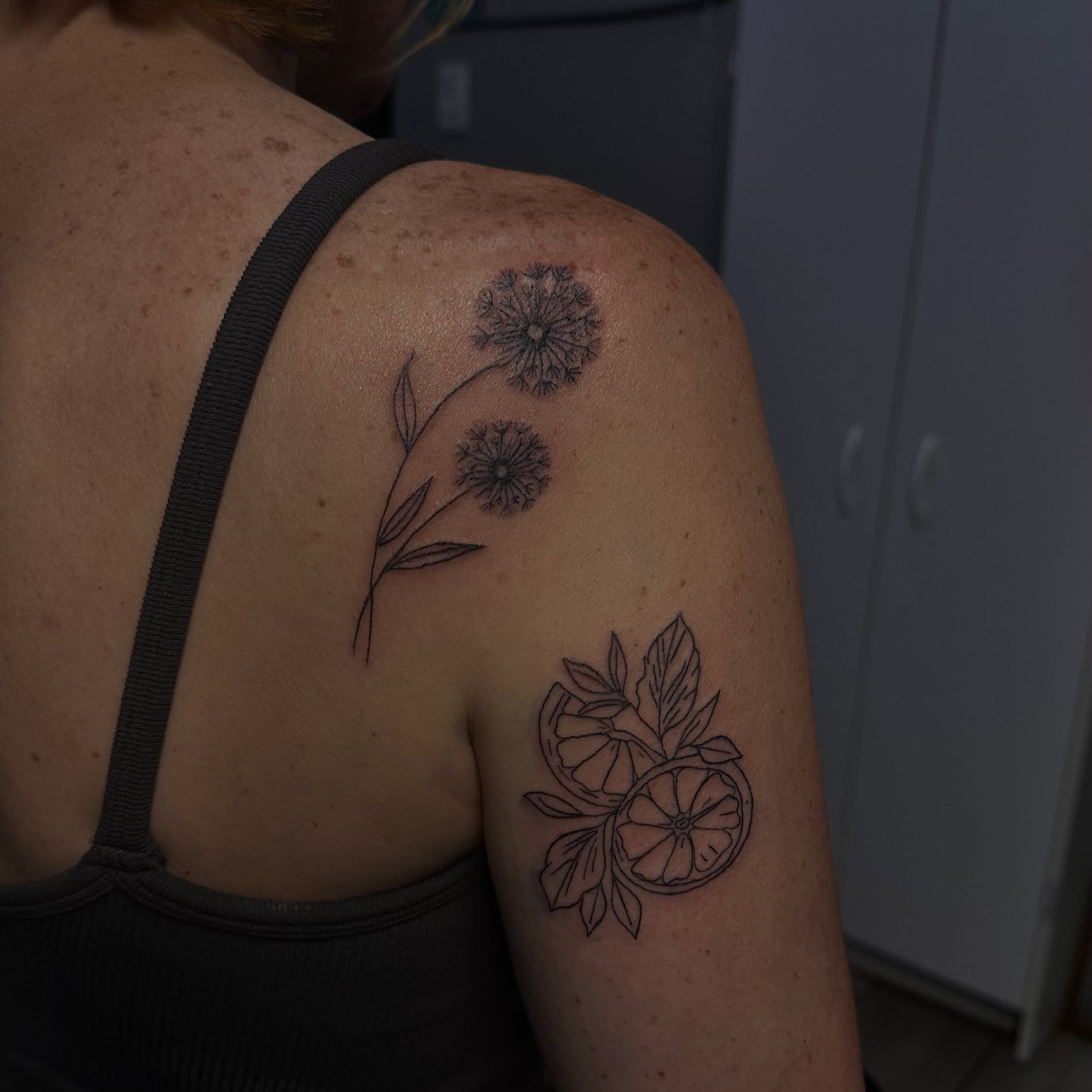 Dandelions and citrus slices black and grey tattoo on the shoulder by Marly Quinn