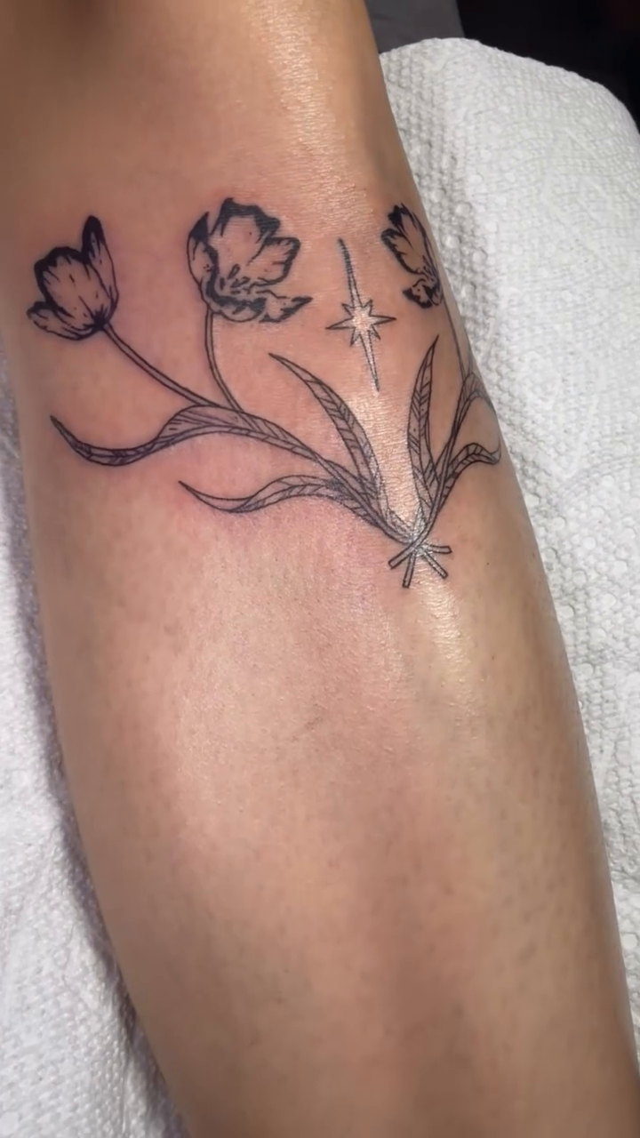 Floral arrangement with stars fine line tattoo on the forearm by Natalie