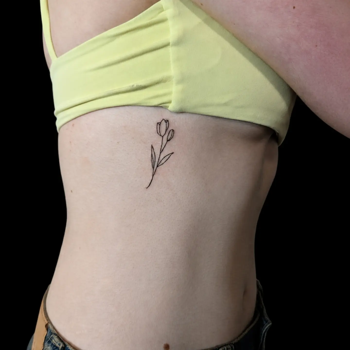 Flower minimalist tattoo on the torso by Tony