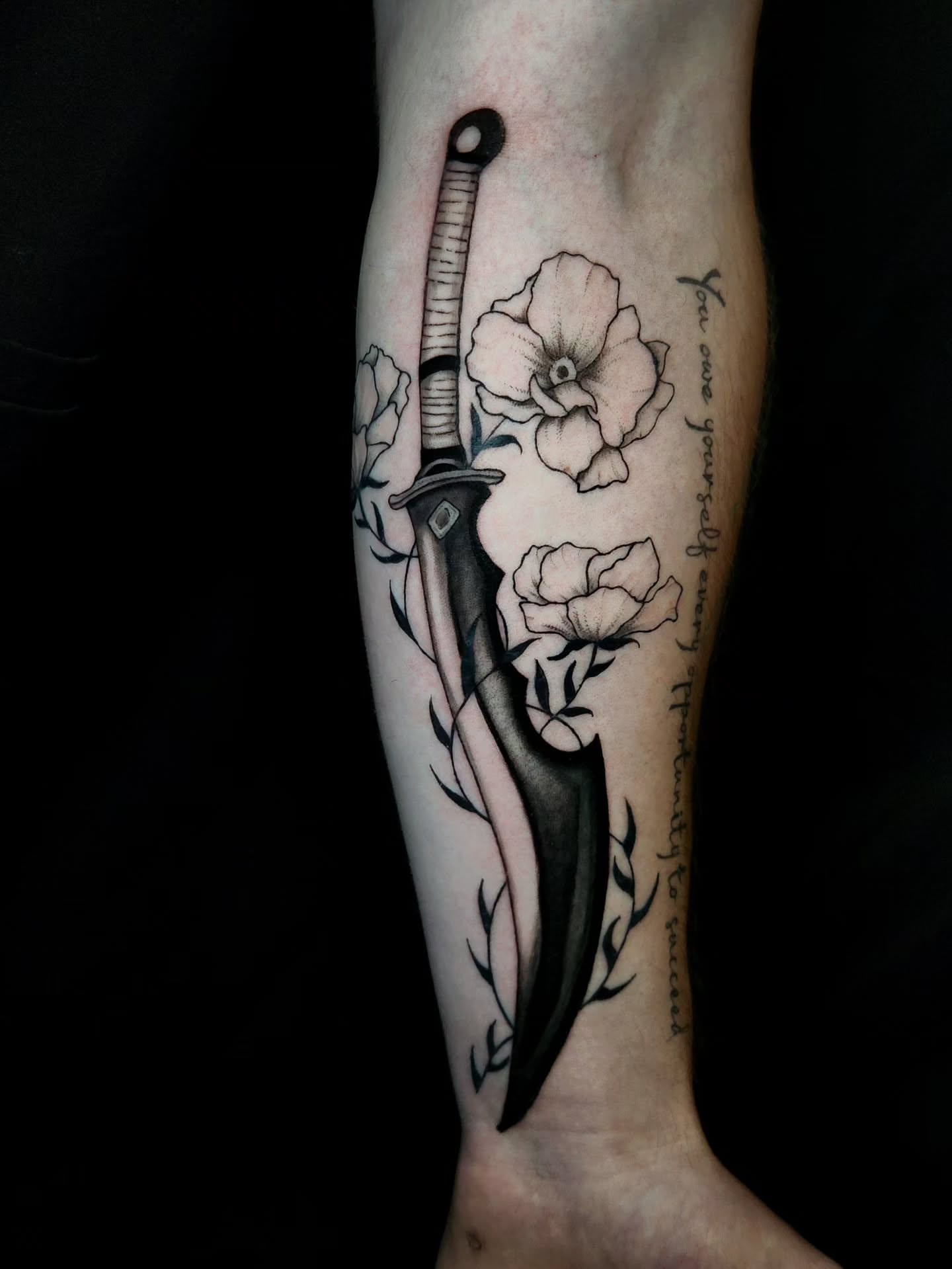 Knife and flowers realism tattoo on the forearm by Ashly Renee