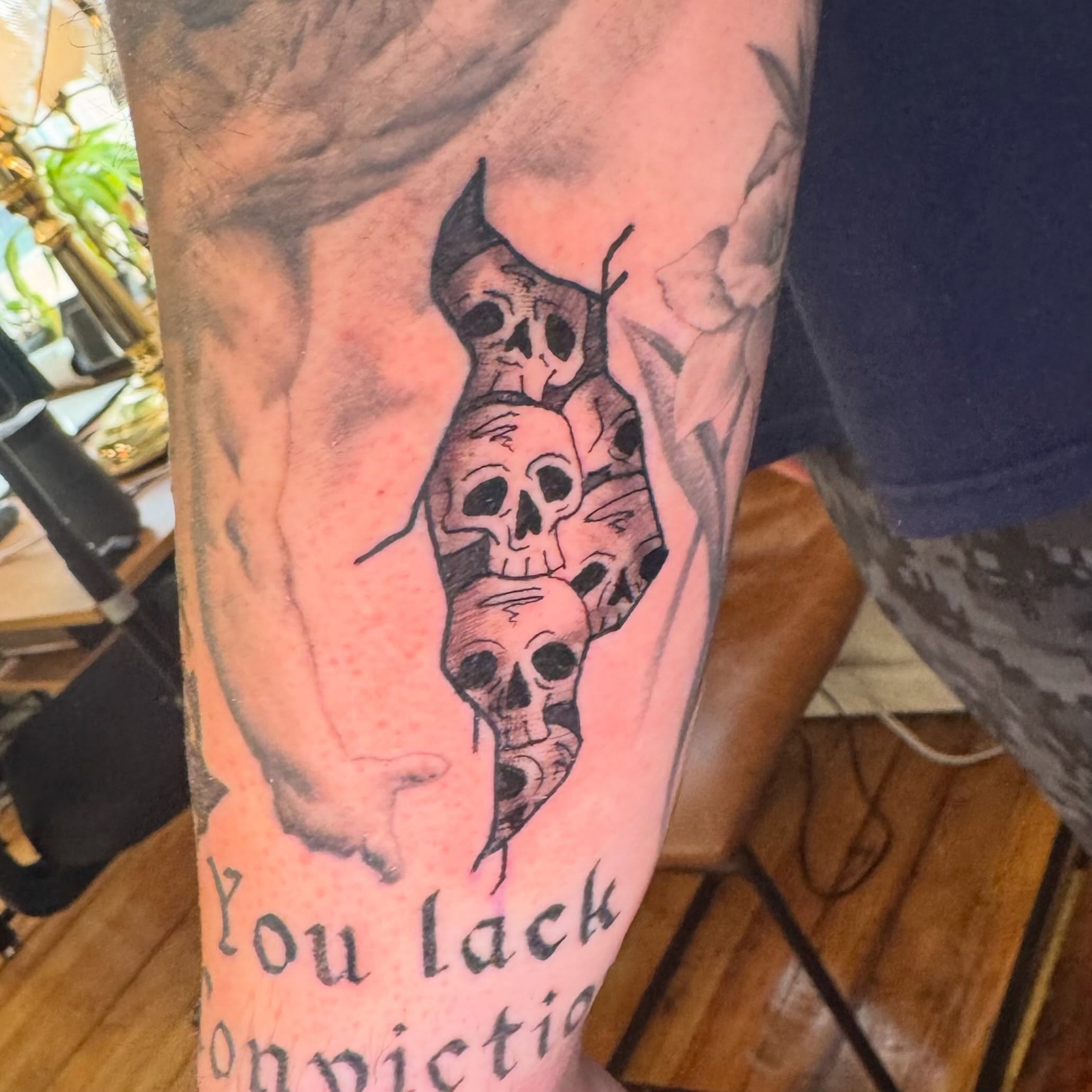 Skulls and text black and grey tattoo on the forearm by Zac Smith-Chevalier