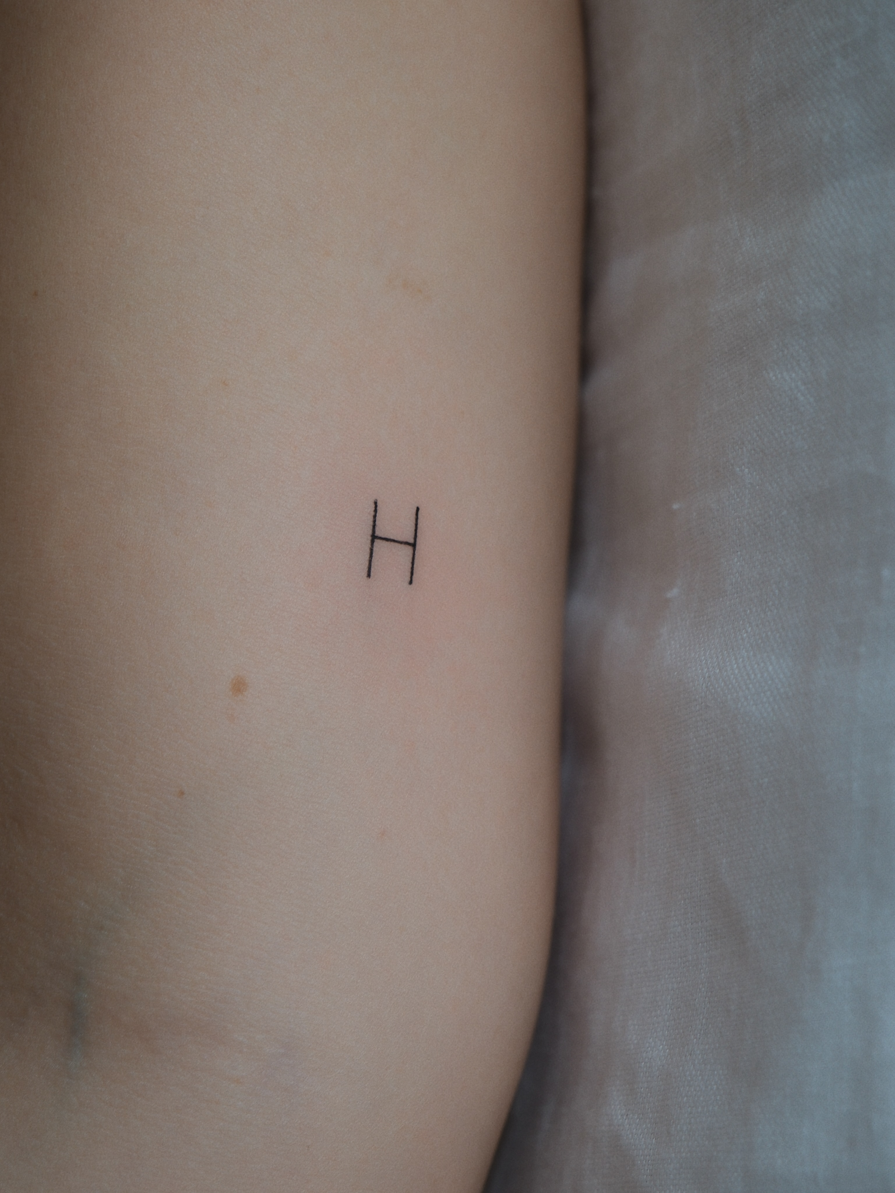 Letter H fine line tattoo on the forearm by Victoria