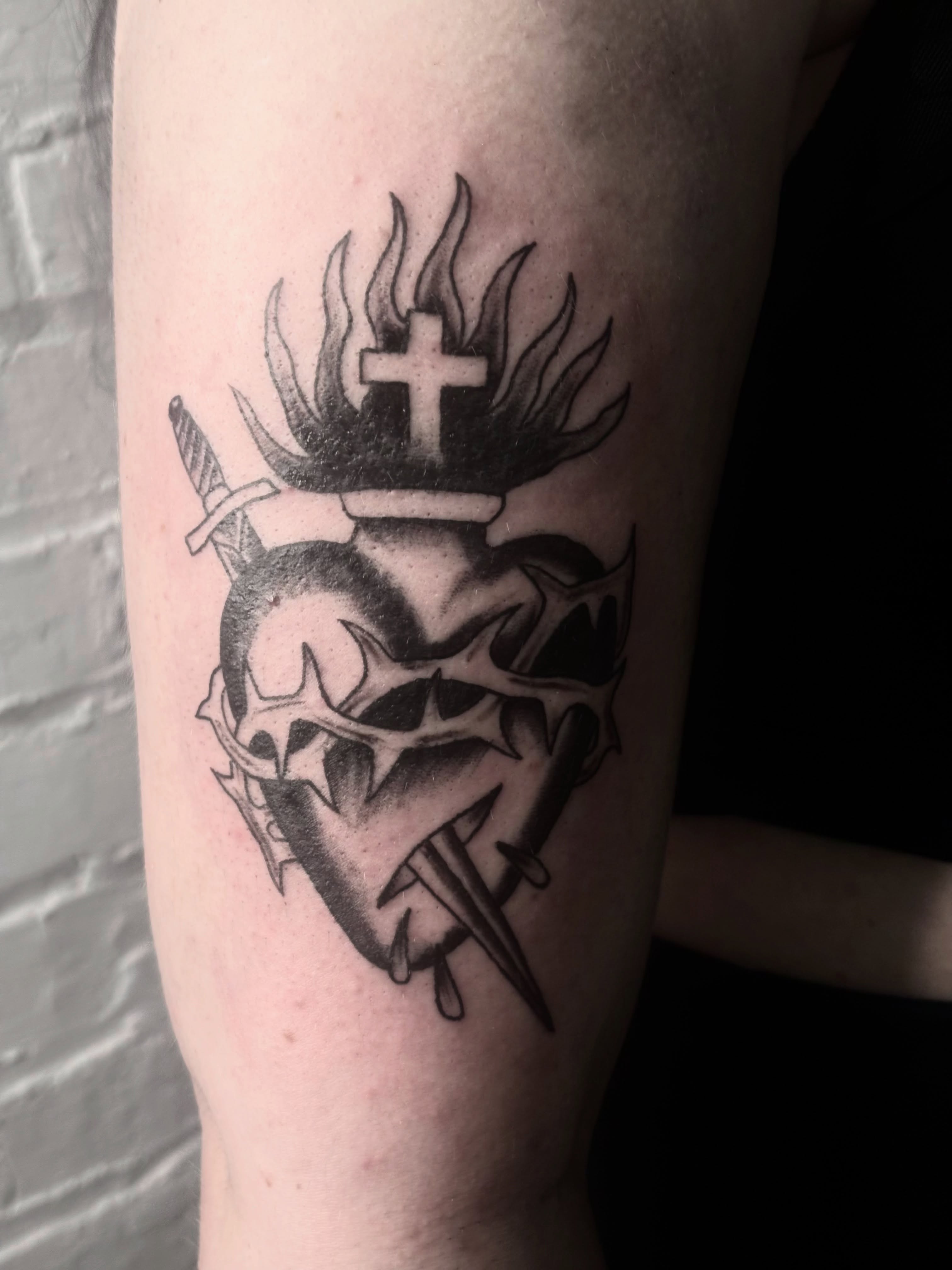 Heart with crown and cross black and grey tattoo on the forearm by Landon Bagley