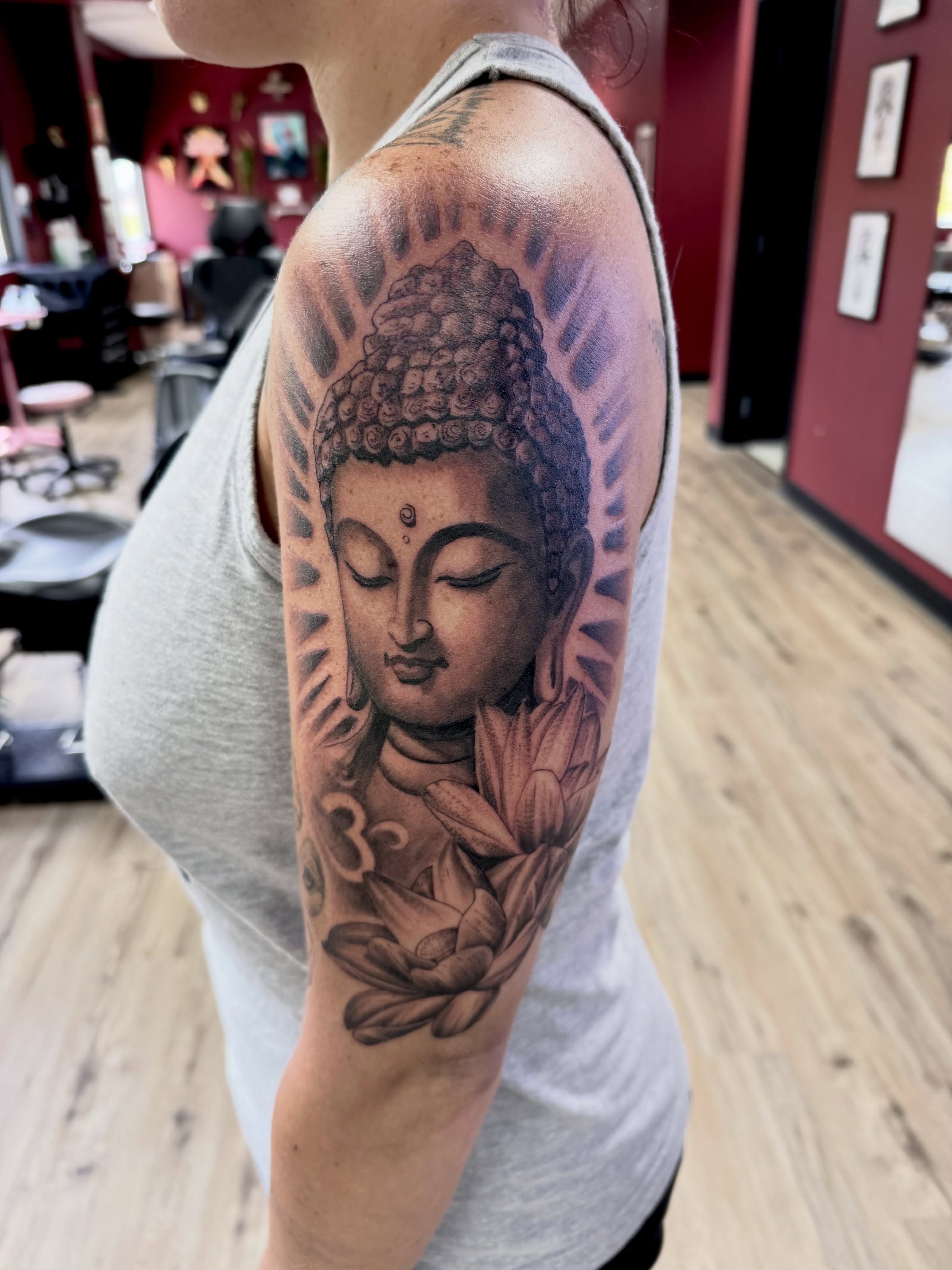 Buddha head realism tattoo on the upper arm by Robbie Bryant