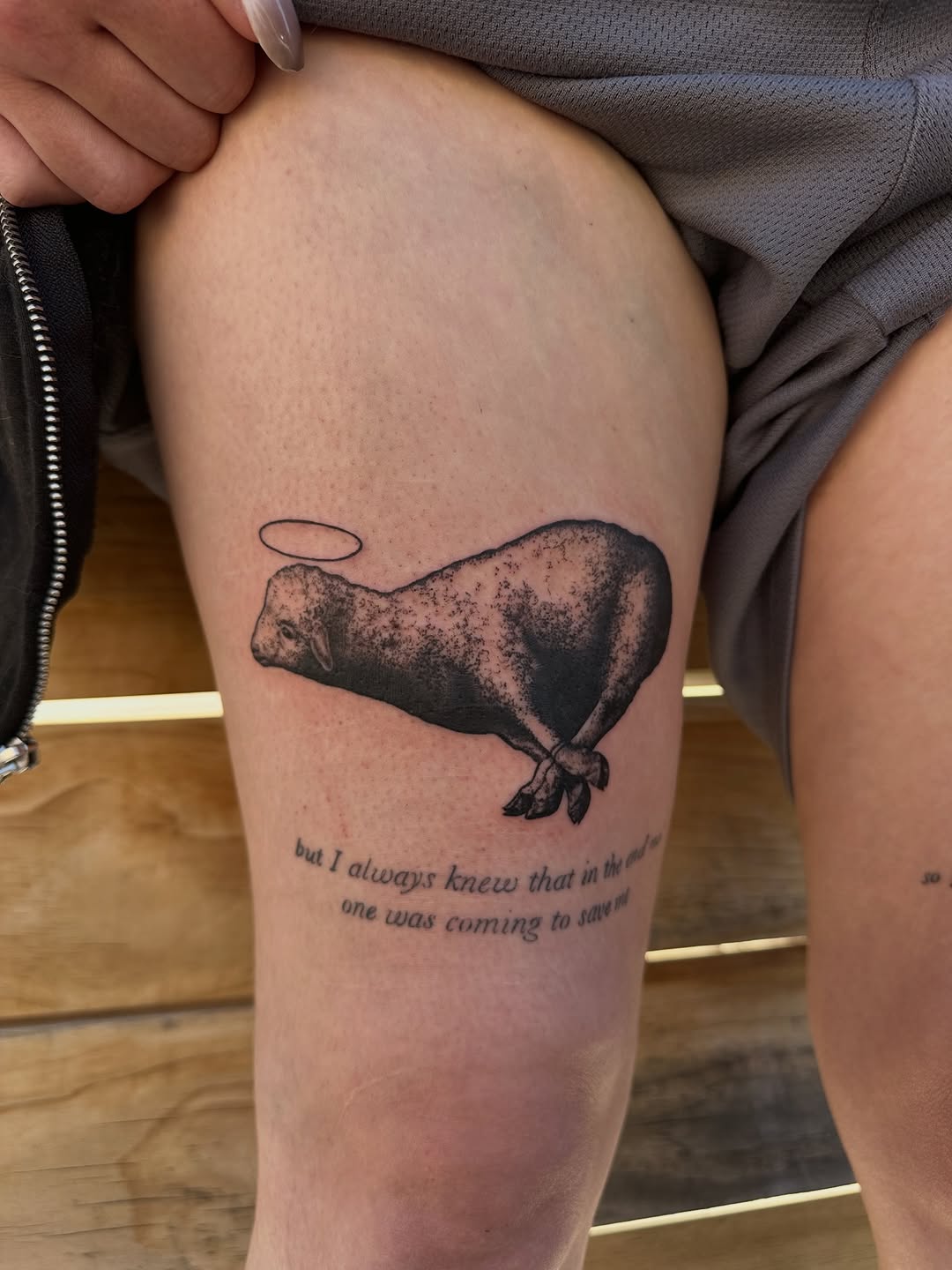 Lamb with halo and text fine line tattoo on the thigh by 𝓡𝓸𝓼𝓮 𝓗𝓪𝔂𝓮𝓼