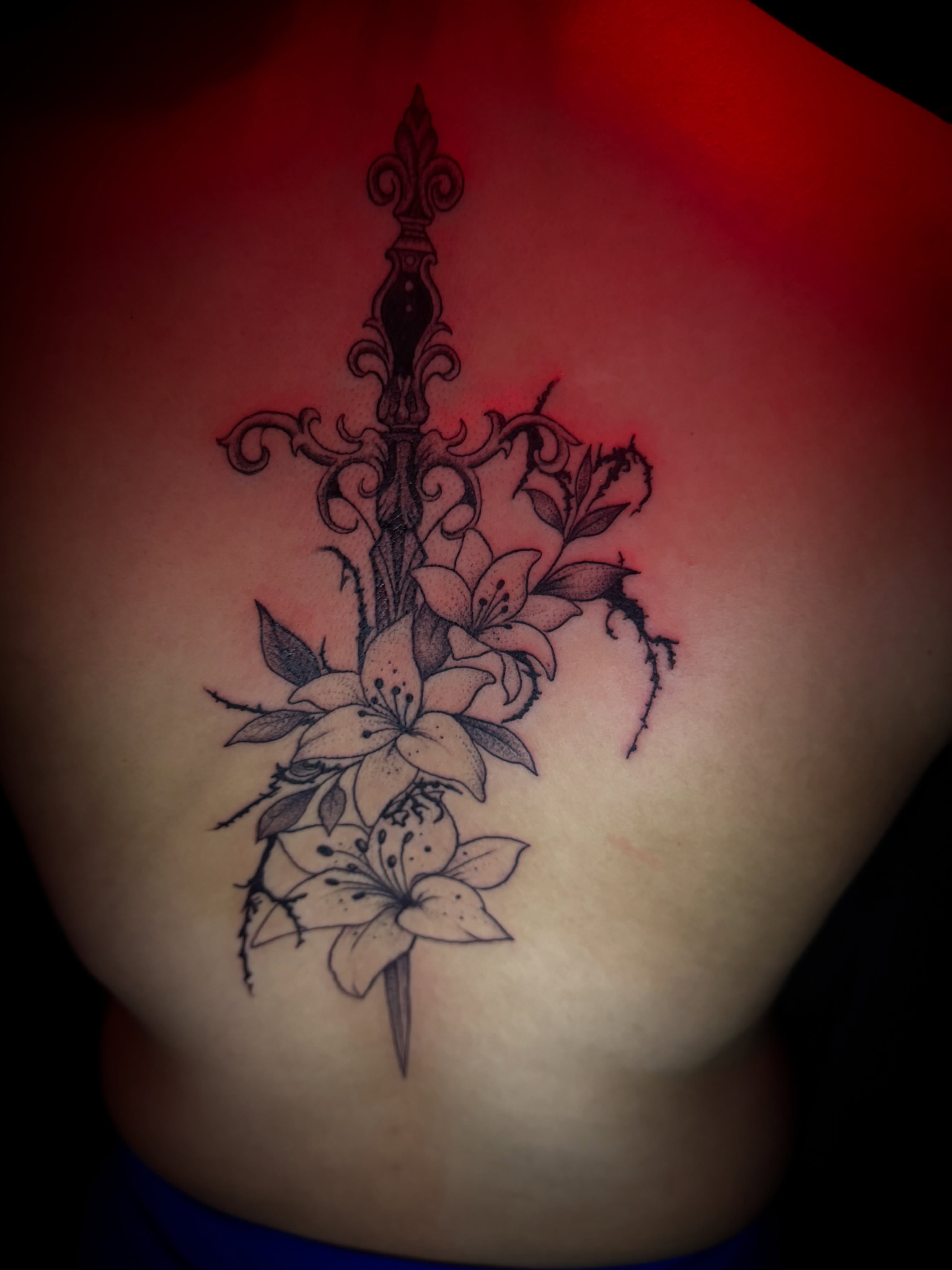 Lilies and sword ornamental tattoo on the ribs by Christa Martinez