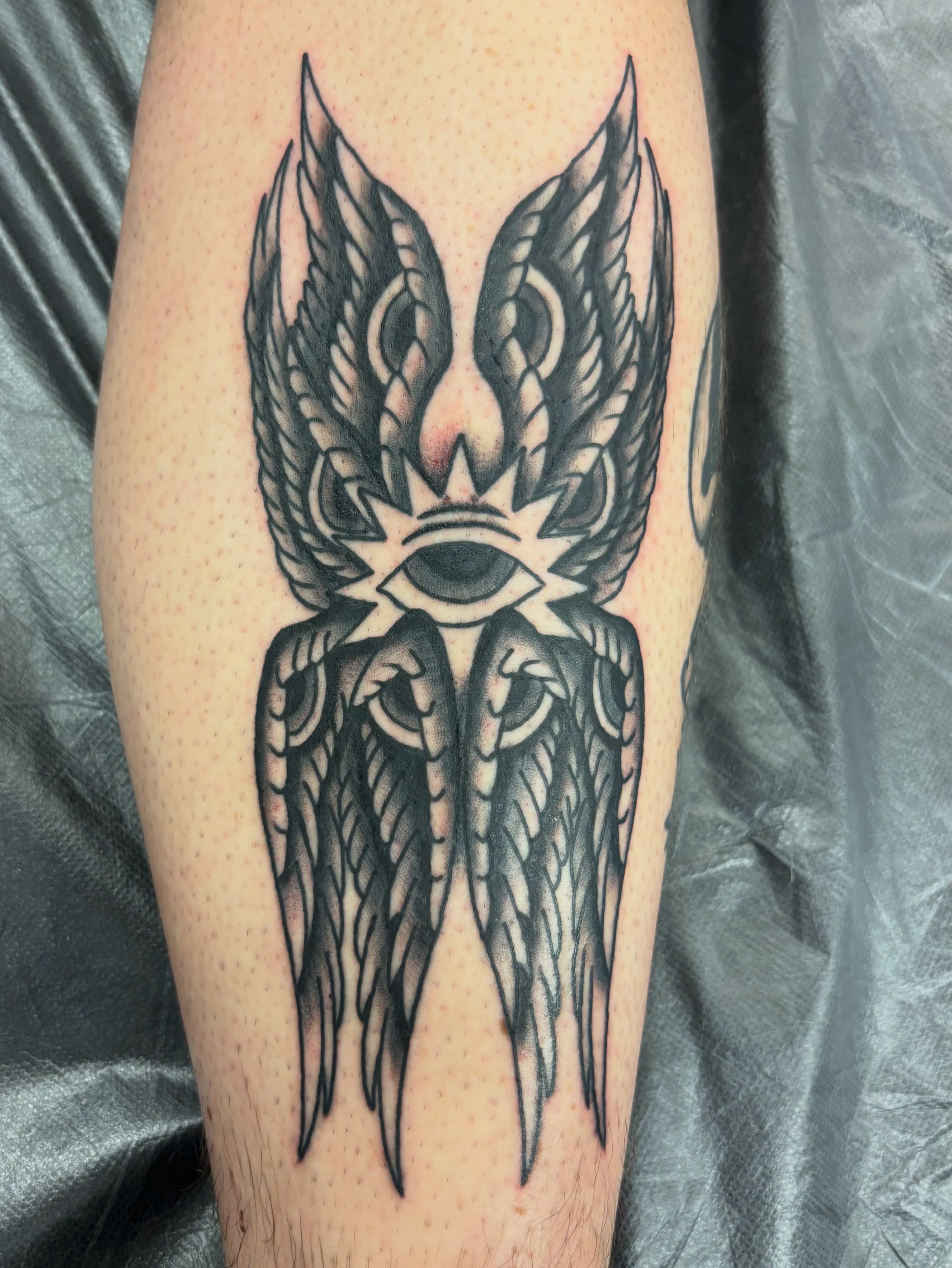 Wings and eye black and grey tattoo on the forearm by Miklo Montoya