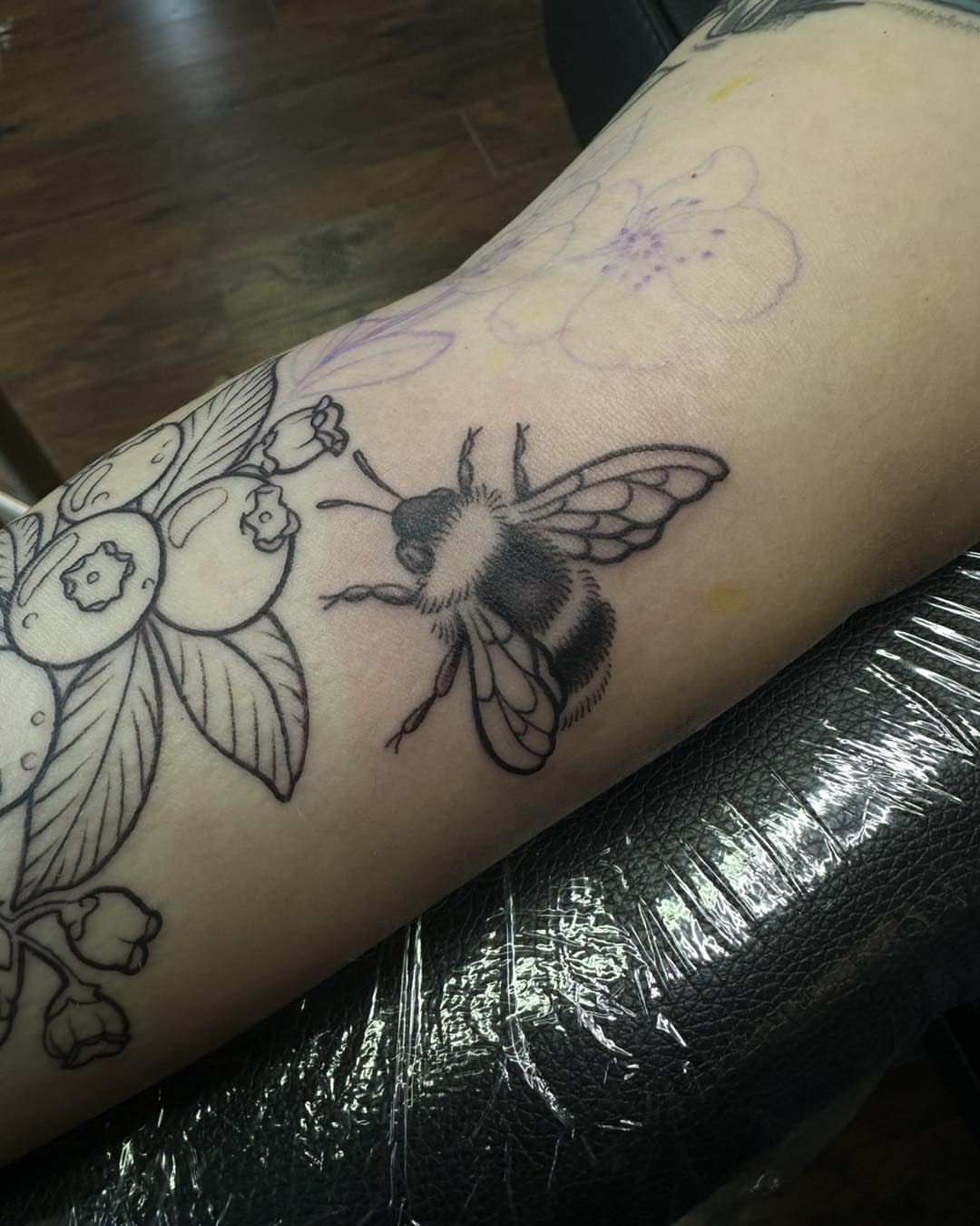 Bee and flowers black and grey tattoo on the forearm by Sarah Nash