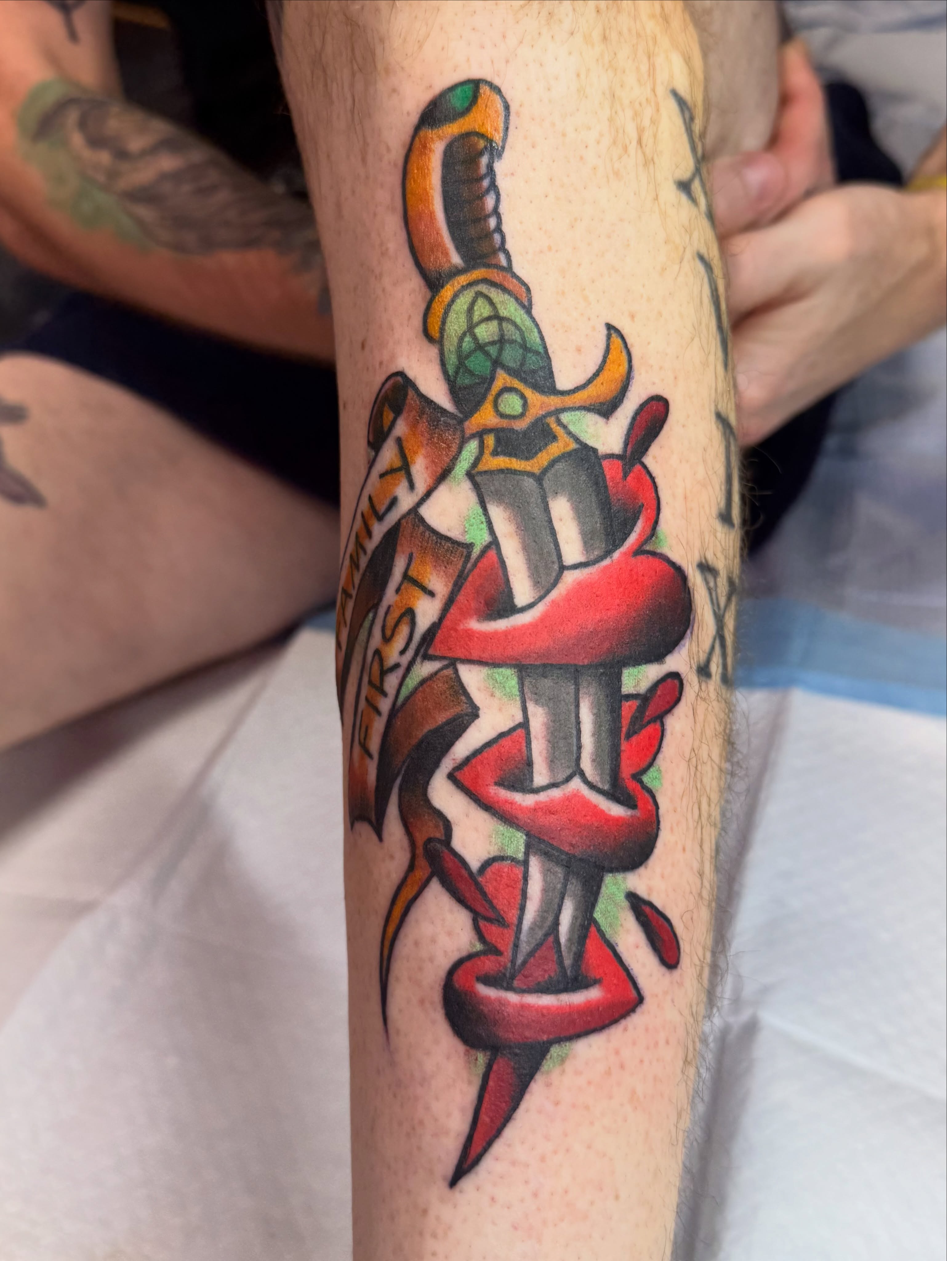 Sword and ribbon American traditional tattoo on the forearm by Shane Bonham