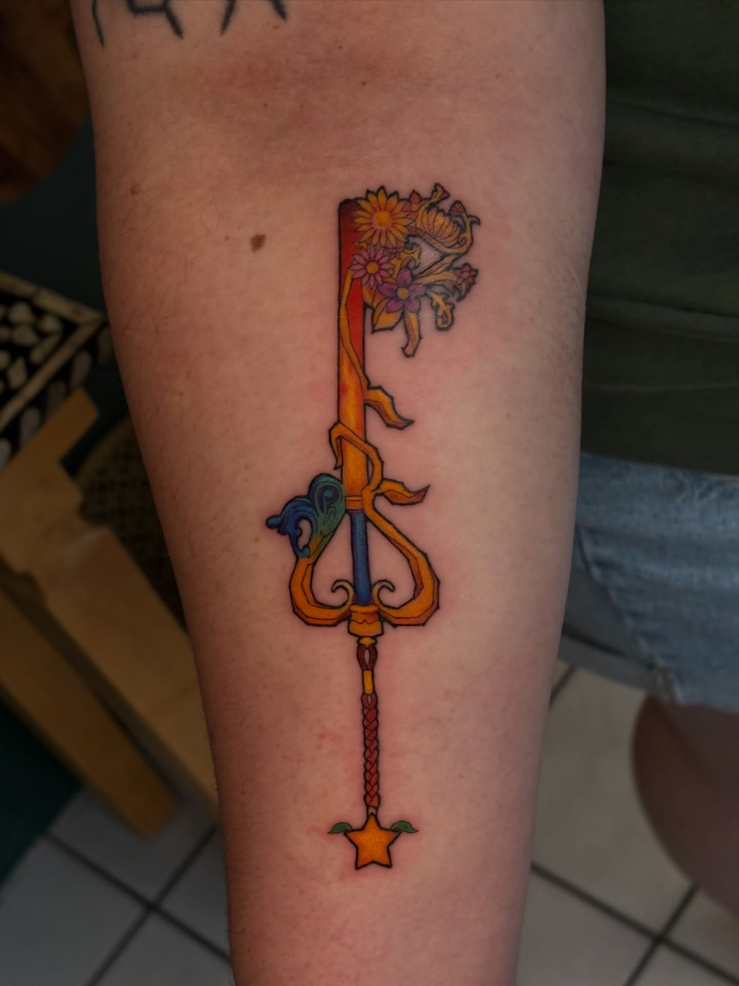 Key with floral elements new school tattoo on the forearm by Chloe Shay