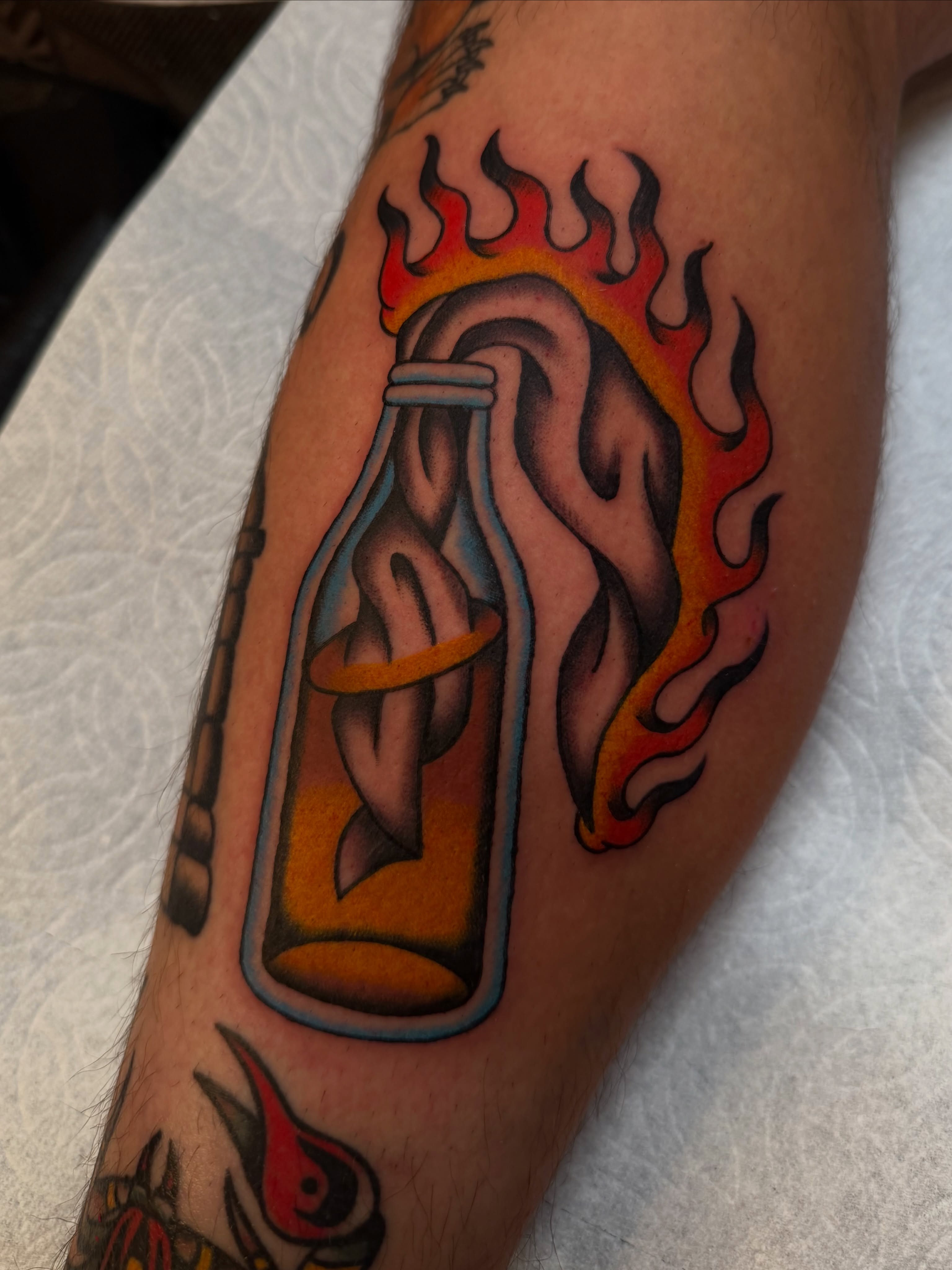 Flaming bottle with ghost American traditional tattoo on the forearm by Tyler Brown, San Diego, California
