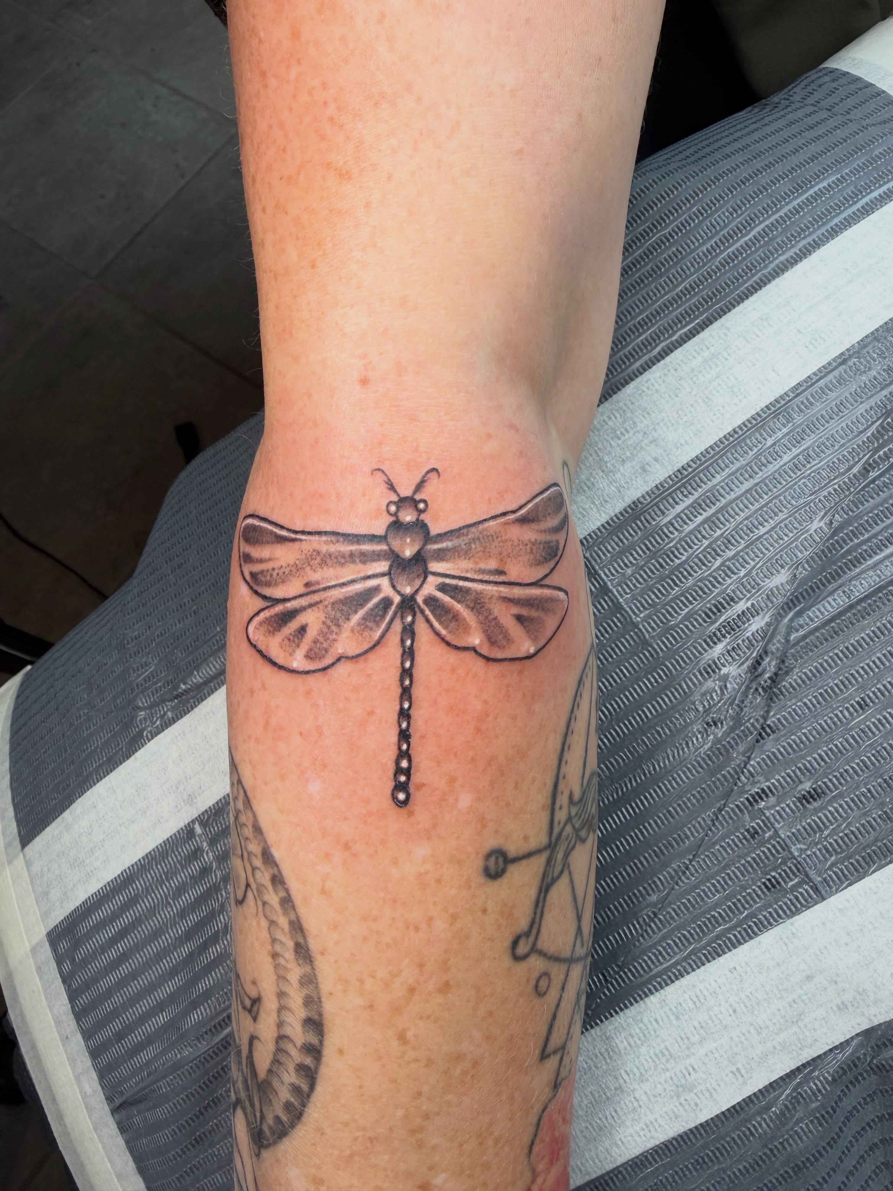 Dragonfly black and grey tattoo on the forearm by Summer Christman