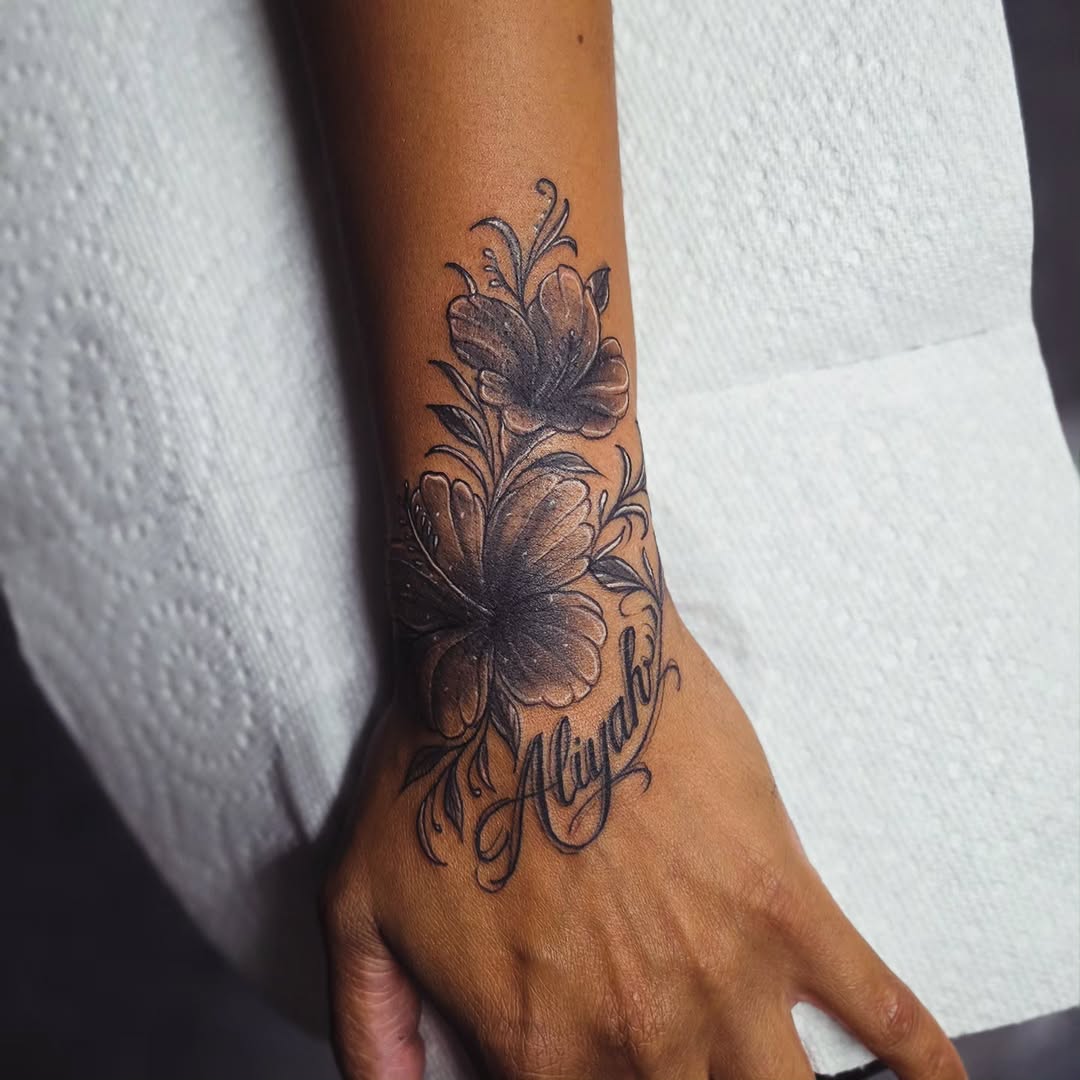 Hibiscus flowers and script name fine line tattoo on the forearm by Kai_Tattoo