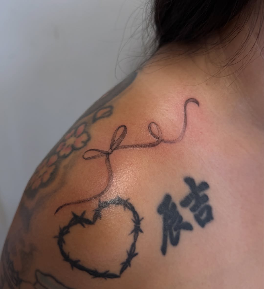Bow and barbed wire black and grey tattoo on the shoulder by Sienna (jj) Hicks