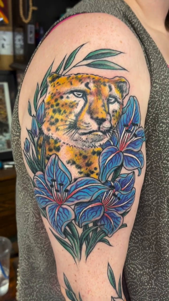 Cheetah surrounded by flowers realism tattoo by Jim Rosal
