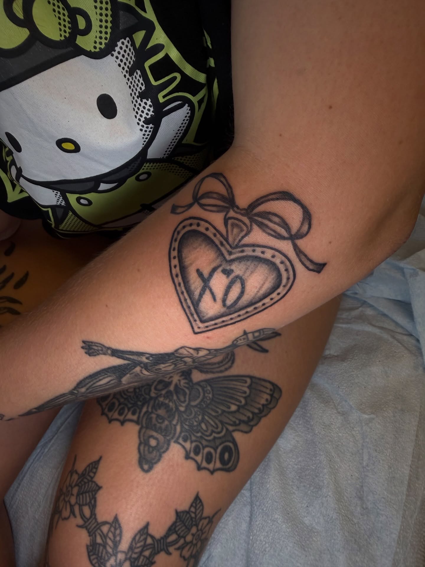 Heart with bow black and grey tattoo on the forearm by Maddie Blosser, Portland, Oregon