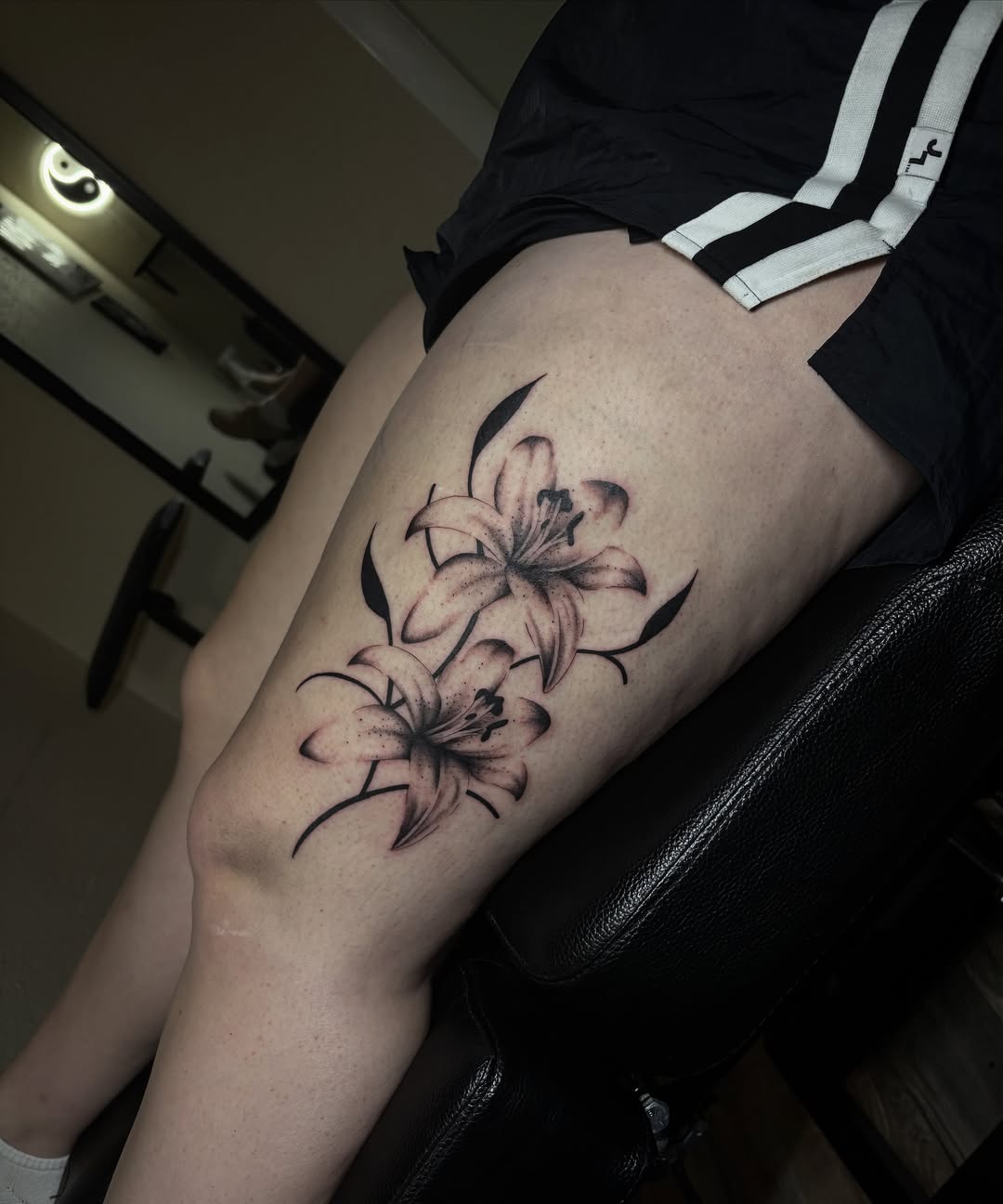 Lilies black and grey tattoo on the thigh by Grace L