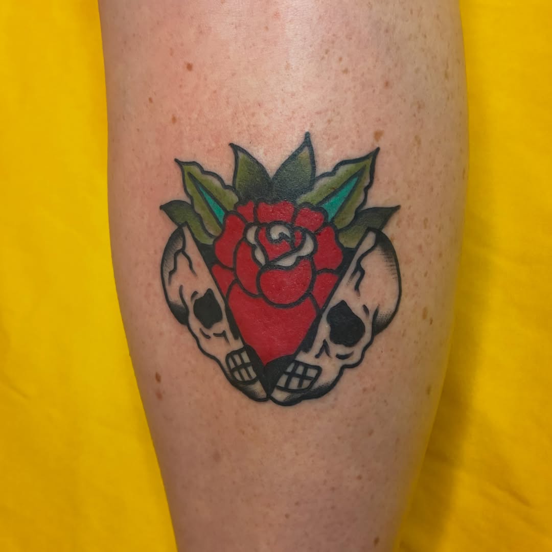 Red rose with skulls American traditional tattoo on the forearm by Kaily McKee