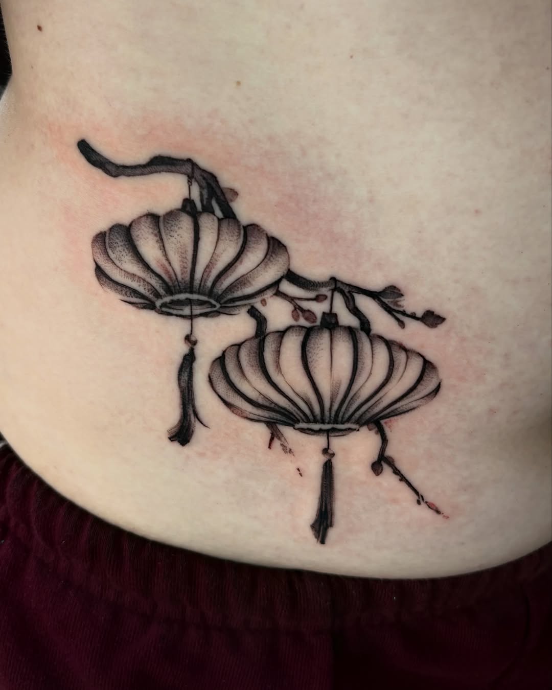 Lanterns on a branch tattoo on the torso by zanna joy