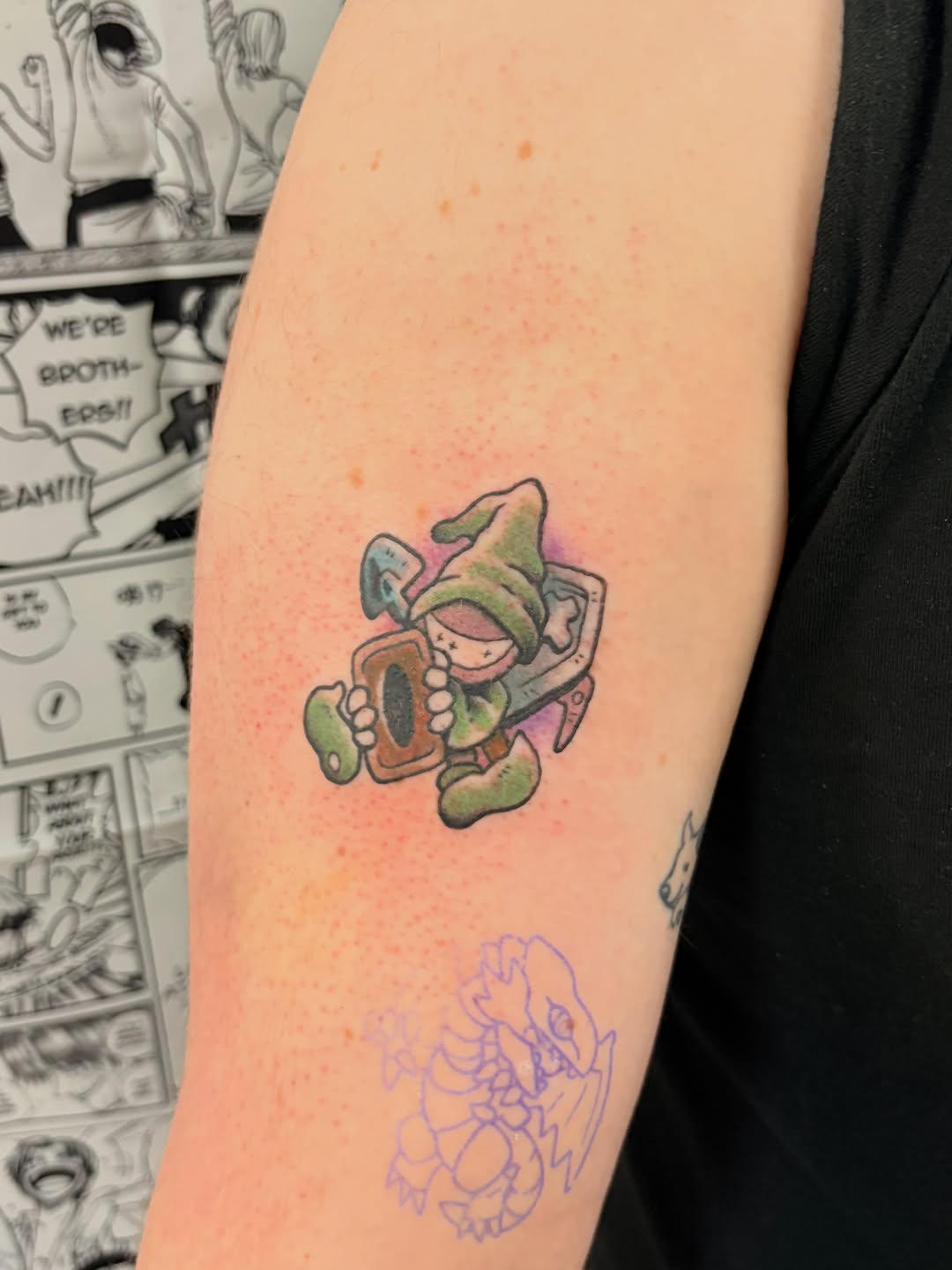 Cartoon character holding a card new school tattoo on the forearm by Chris, Cleveland, Ohio