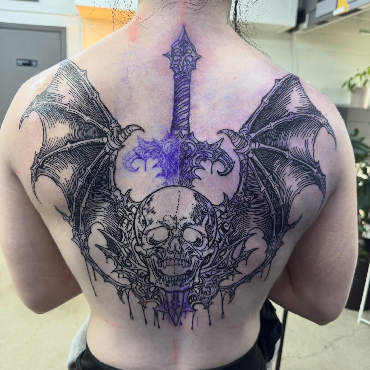 Skull and bat wings dark realism tattoo on the back by Brandiane Wells