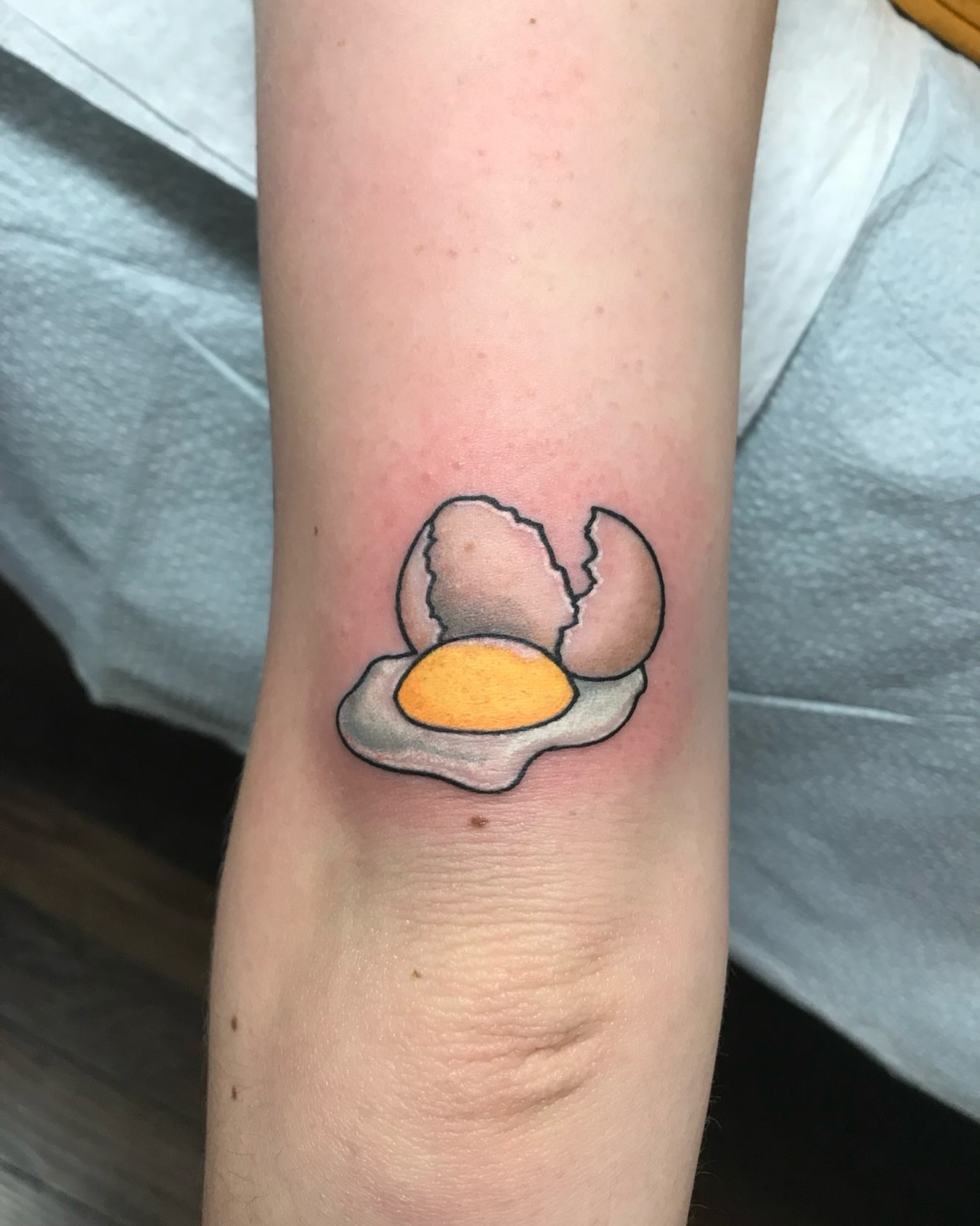 Fried egg realism tattoo on the forearm by Ashley Antolin
