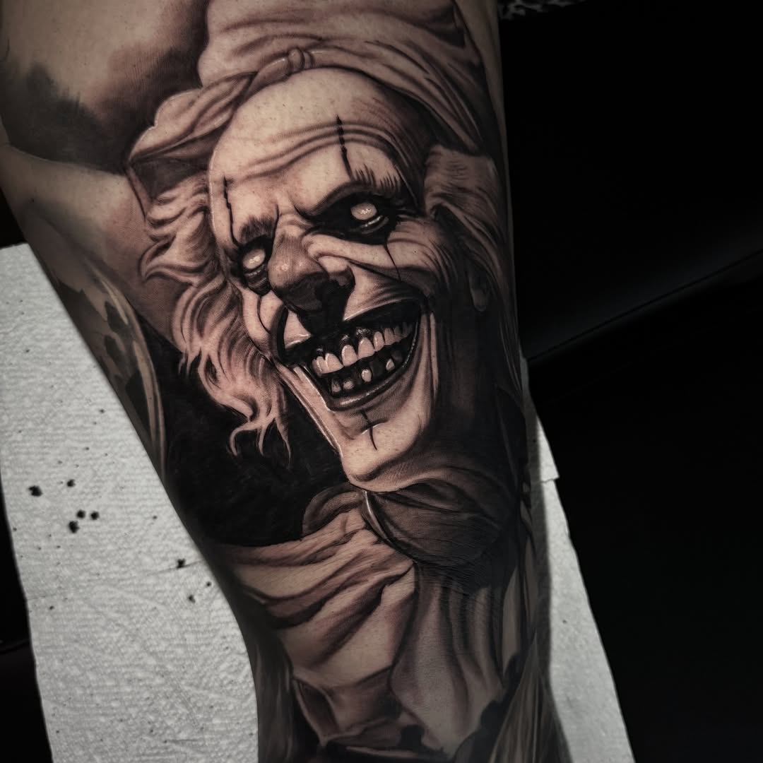 Creepy clown portrait realism tattoo on the forearm by Jake Fujimura