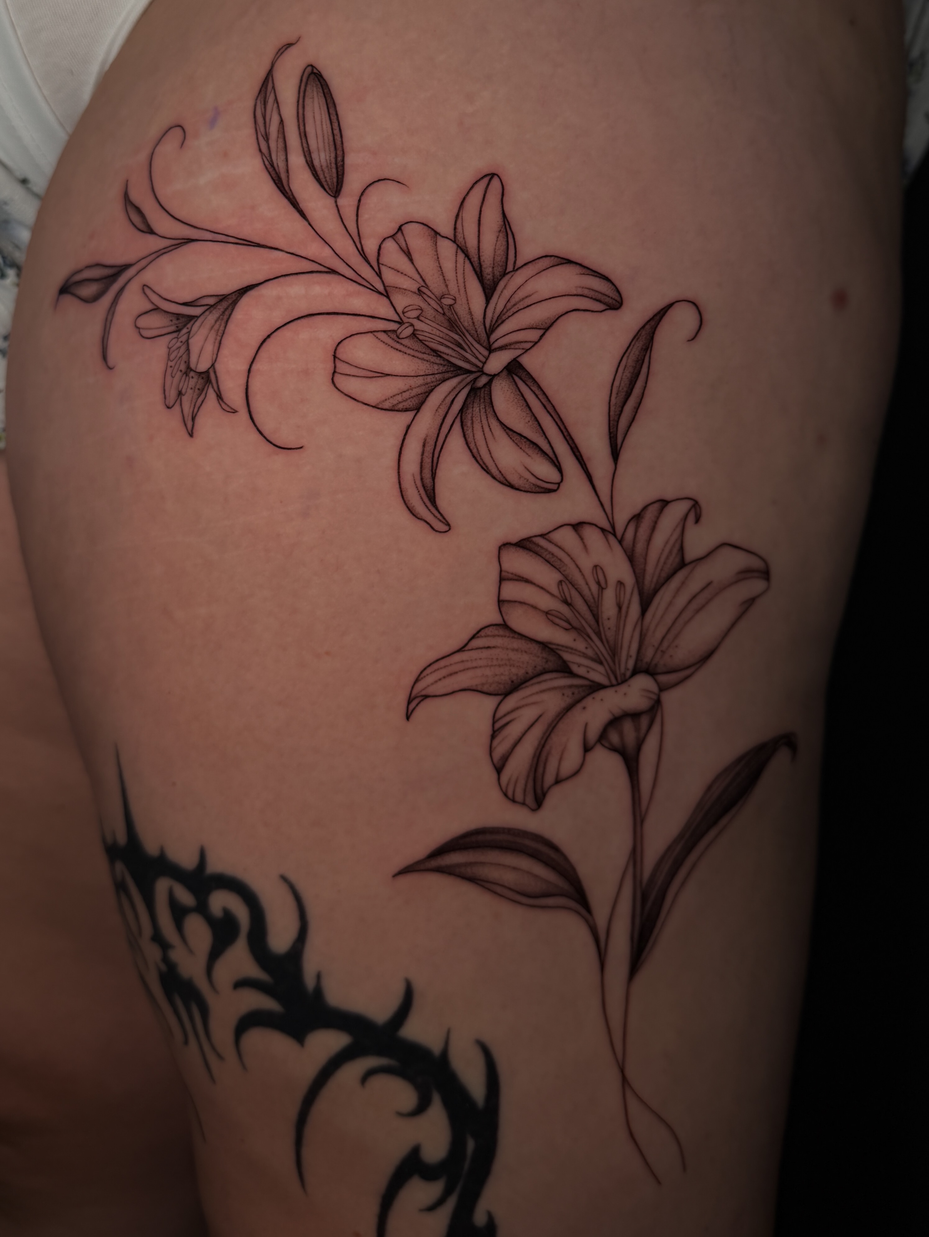 Lilies black and grey tattoo on the thigh by Marianne