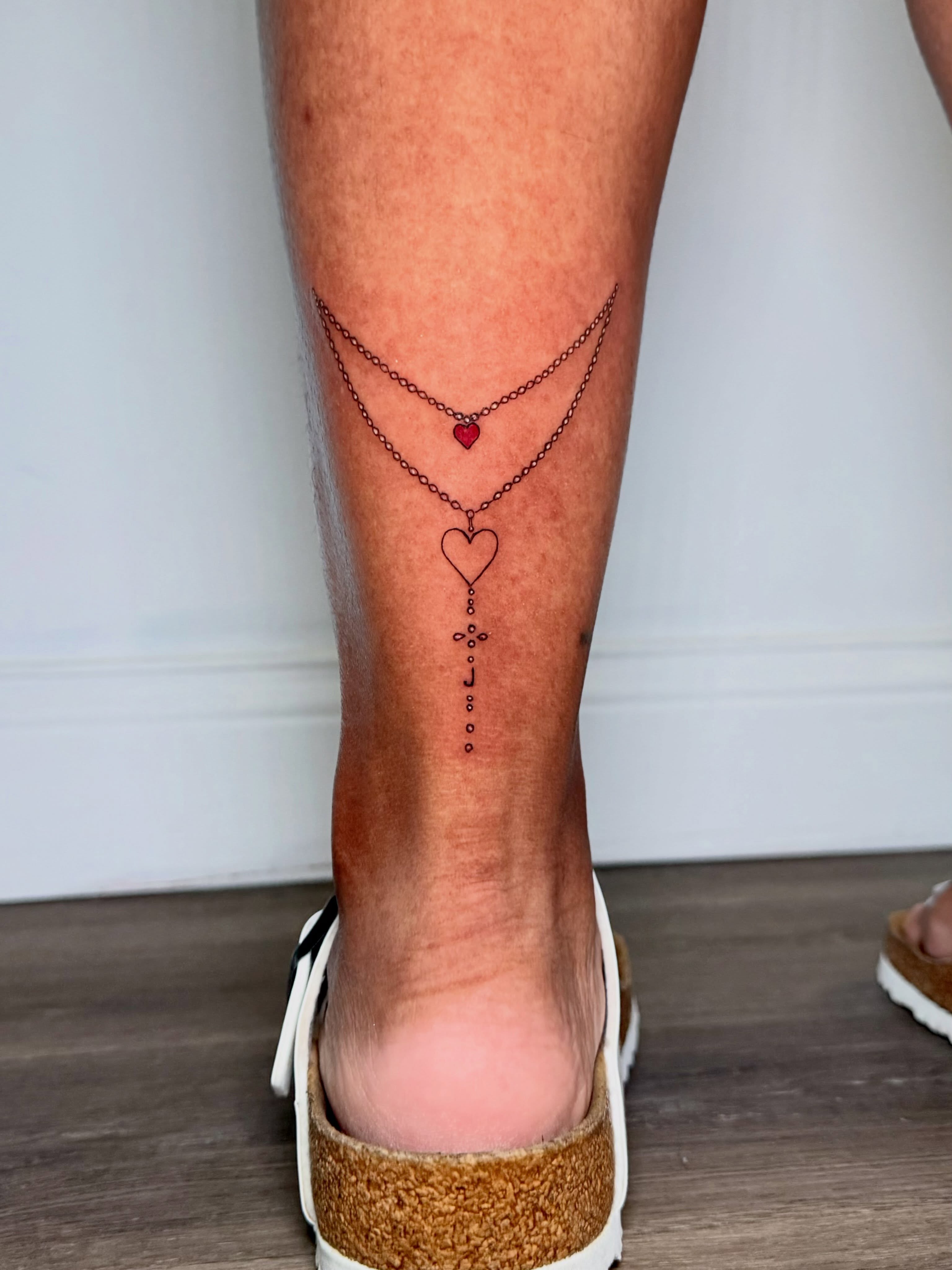 Chain and heart fine line tattoo on the calf by Fine Line Tattoo Artist
